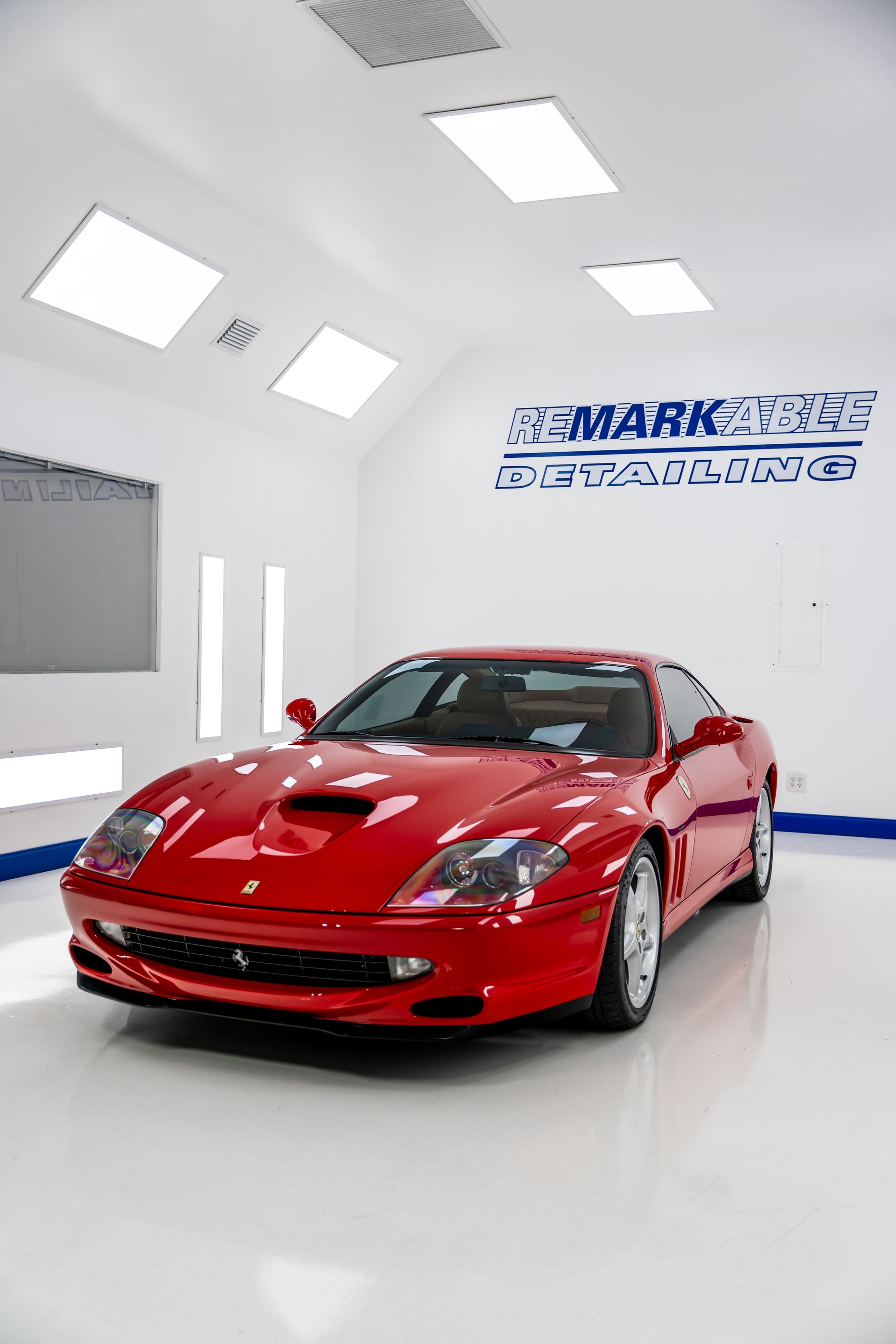 A red ferrari is parked in a showroom.