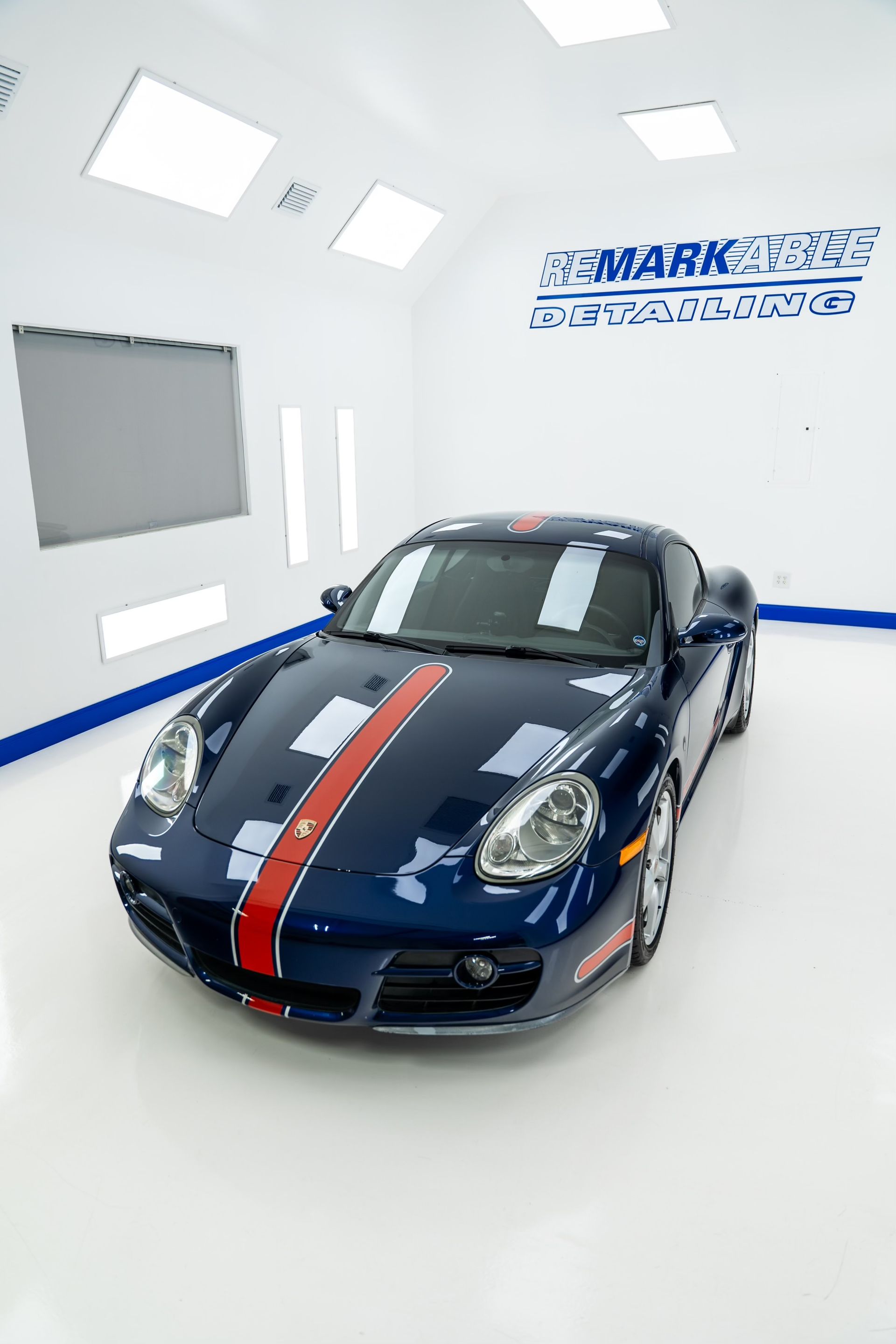 A blue sports car with a red and white stripe on the side is parked in a garage.