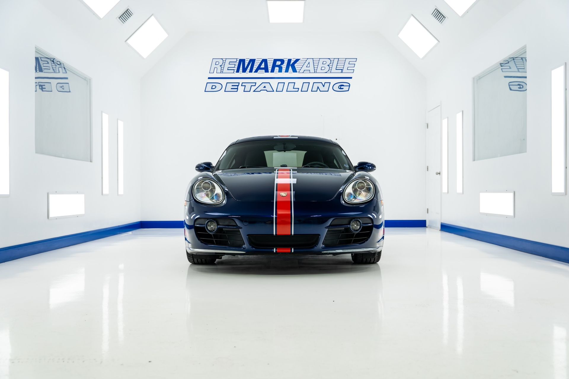 A blue sports car is parked in a paint booth.