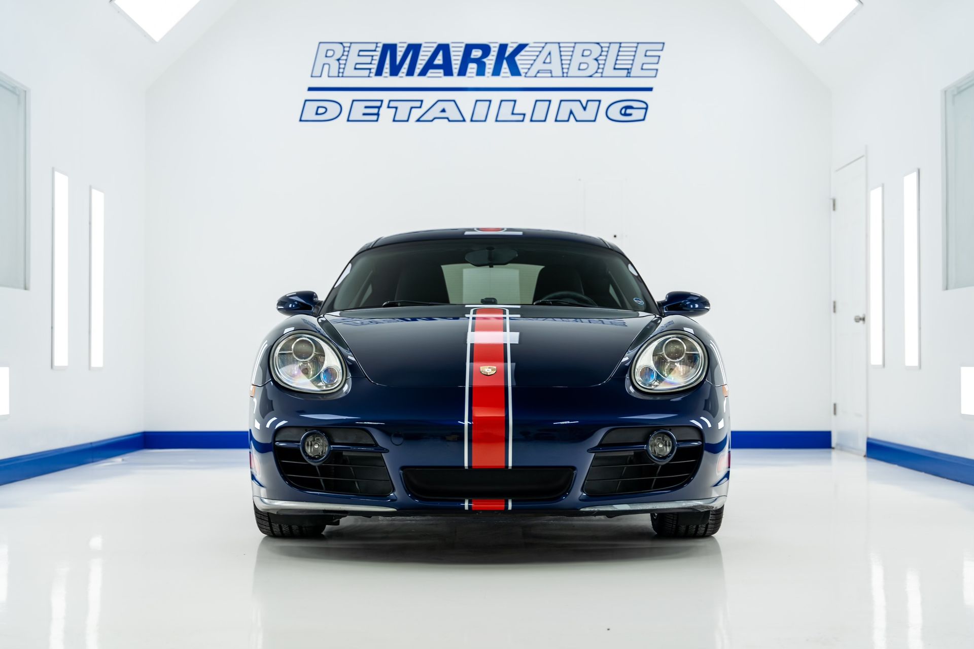 A blue car with a red white and blue stripe is parked in a showroom.