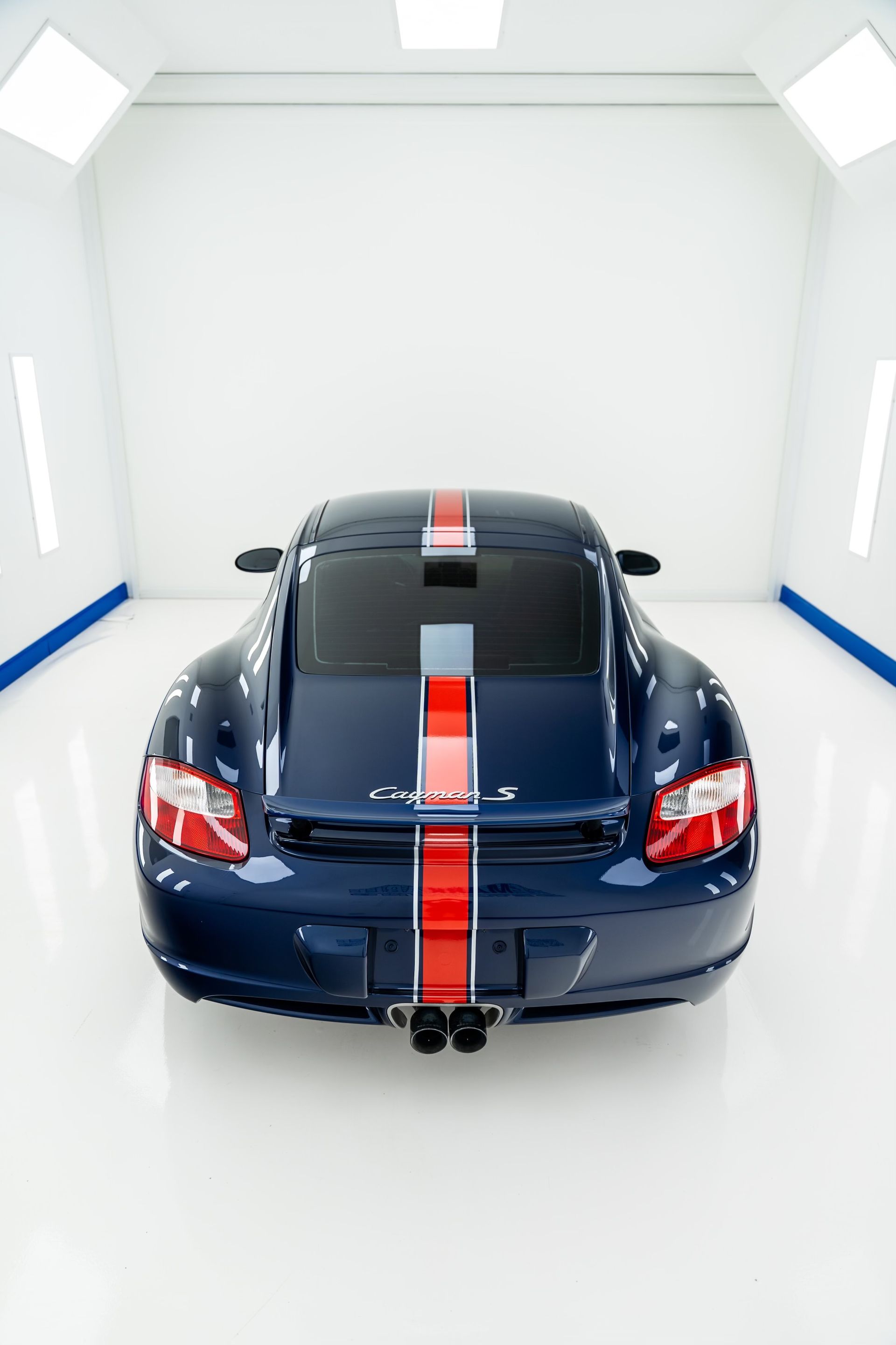 A blue sports car with red and white stripes is parked in a garage.
