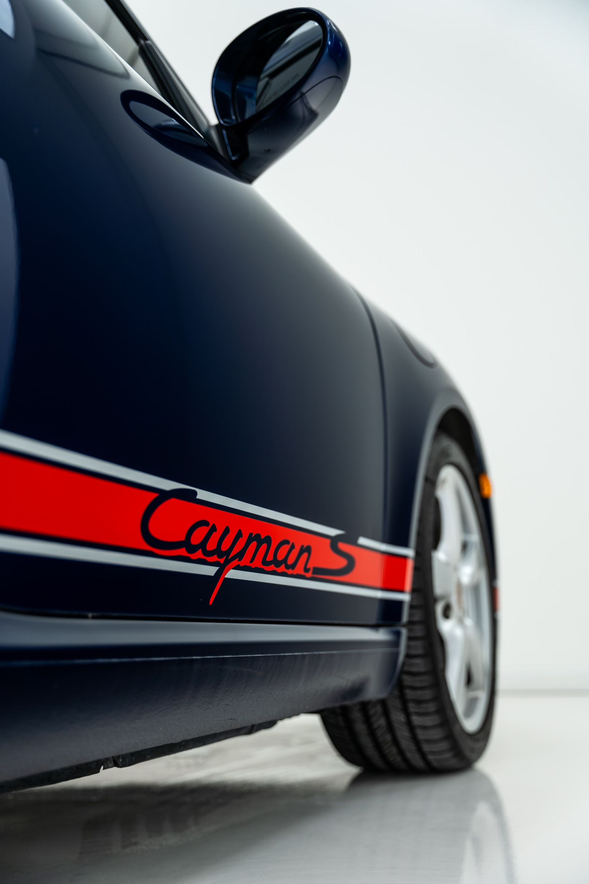 A blue porsche cayman with a red stripe on the side