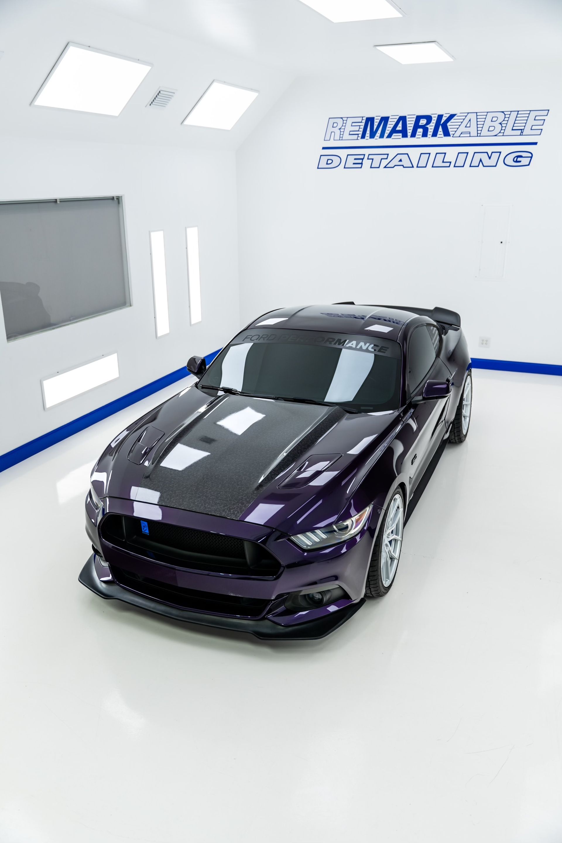 A purple mustang is parked in a paint booth.