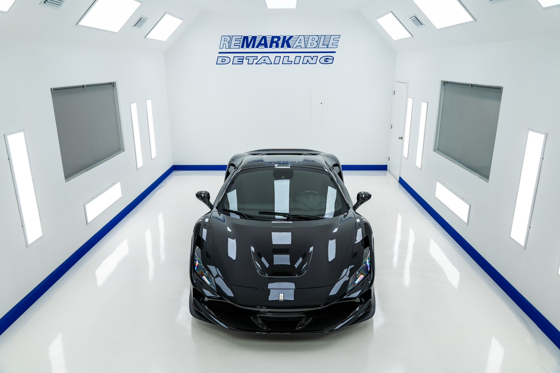 A black sports car is parked in a paint booth.