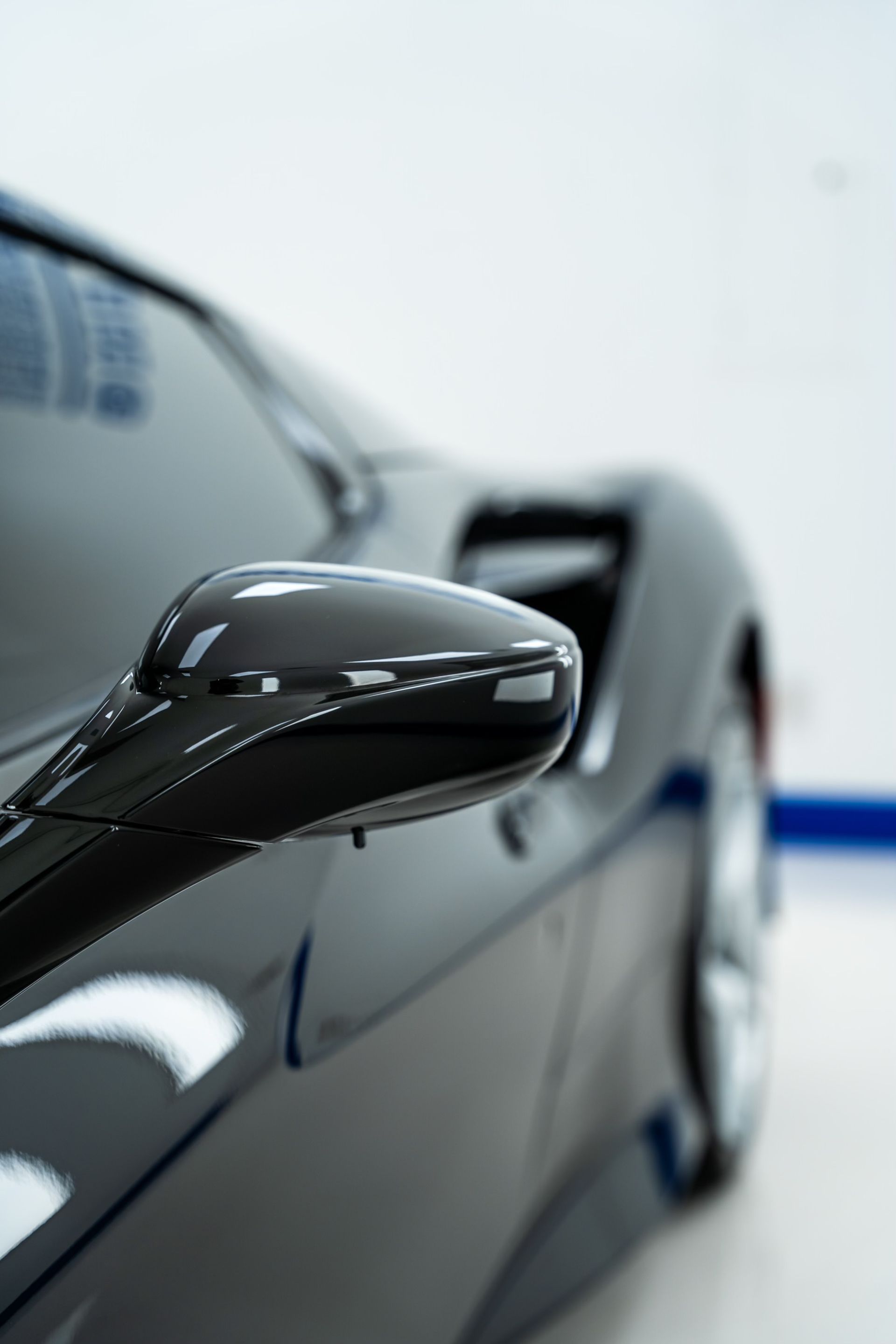 A black sports car is parked in a garage with a white wall in the background