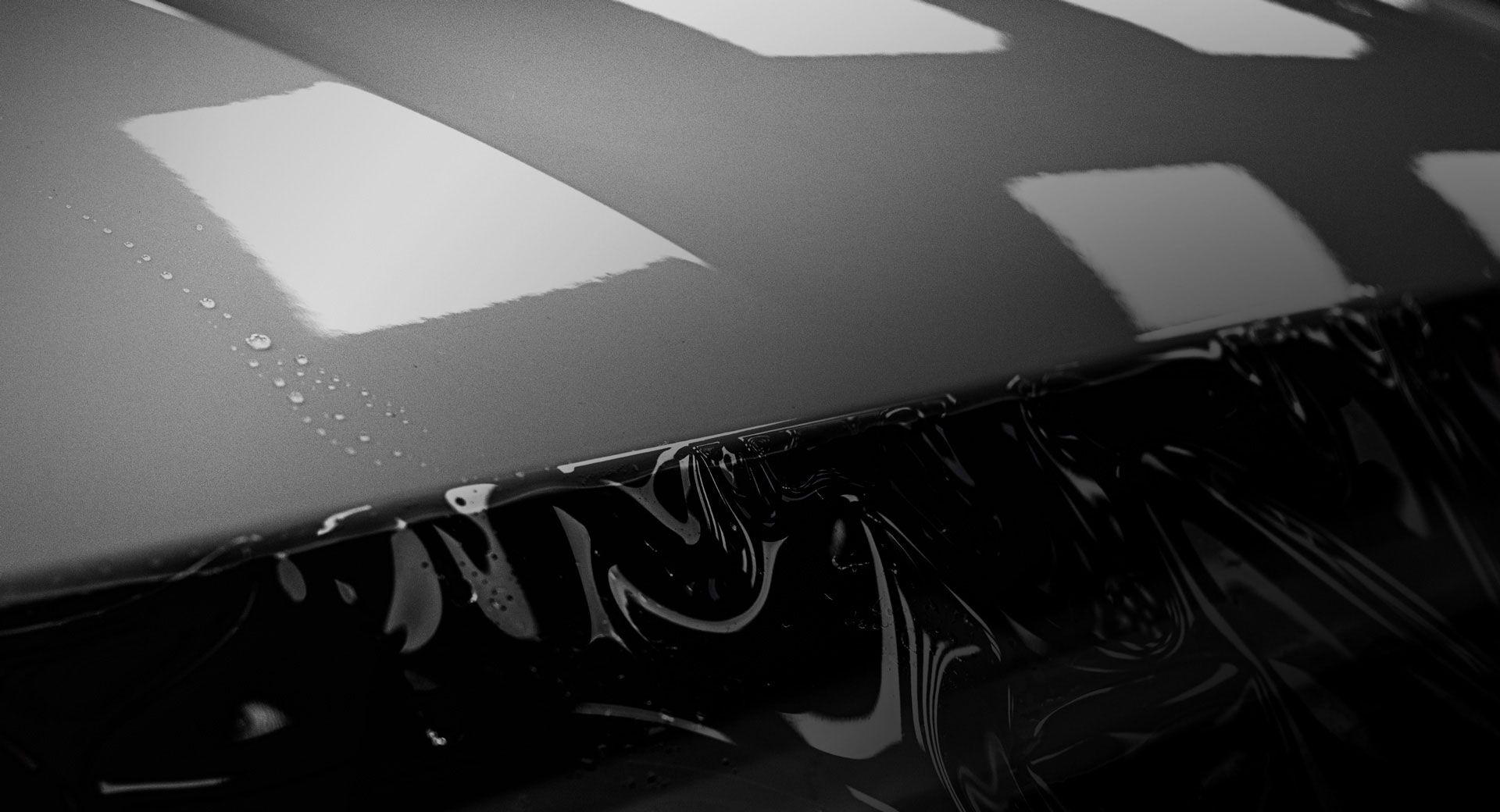 A black and white photo of a car hood wrapped in plastic.