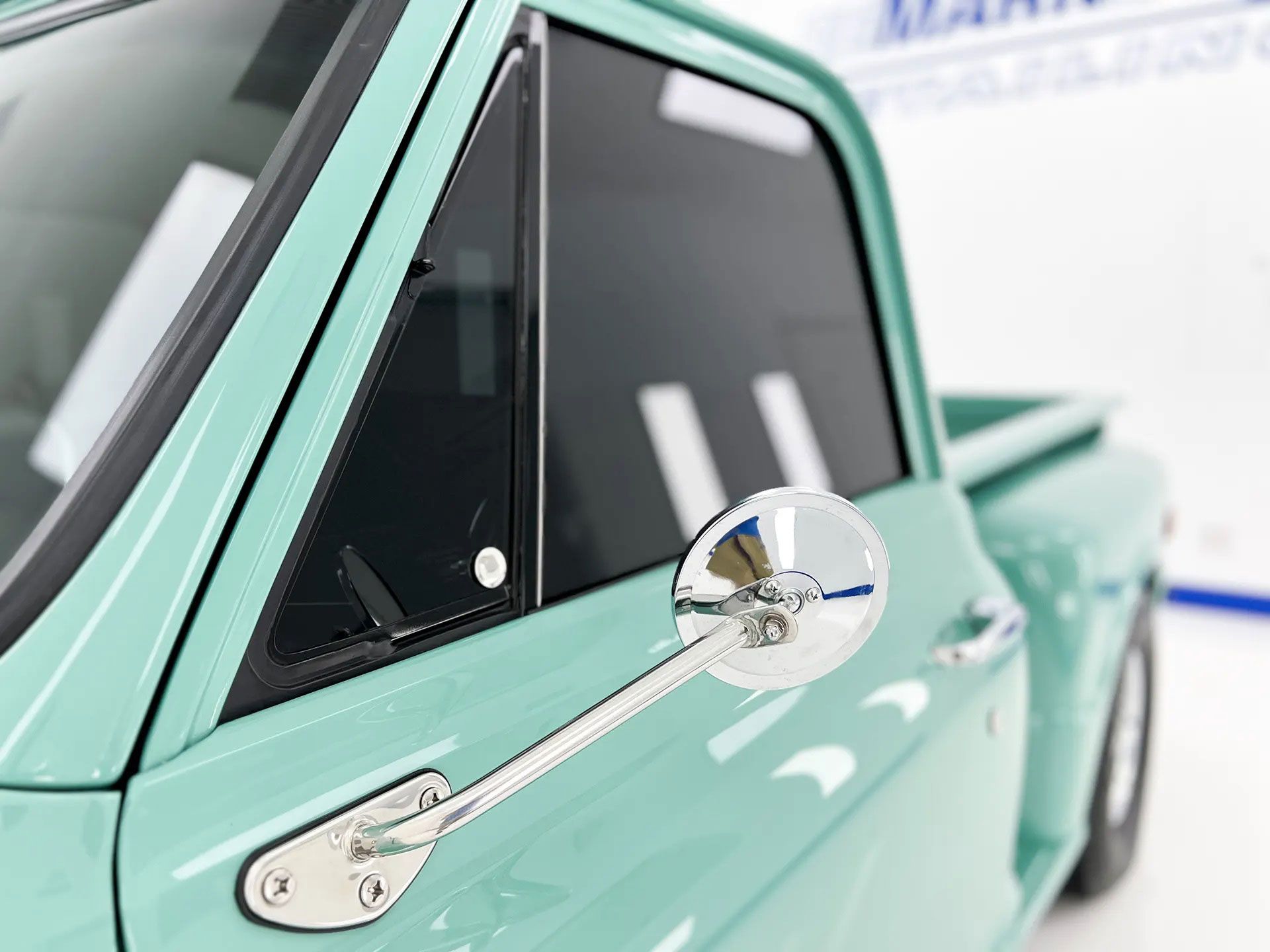 A close up of a green truck with a mirror on the side of it.