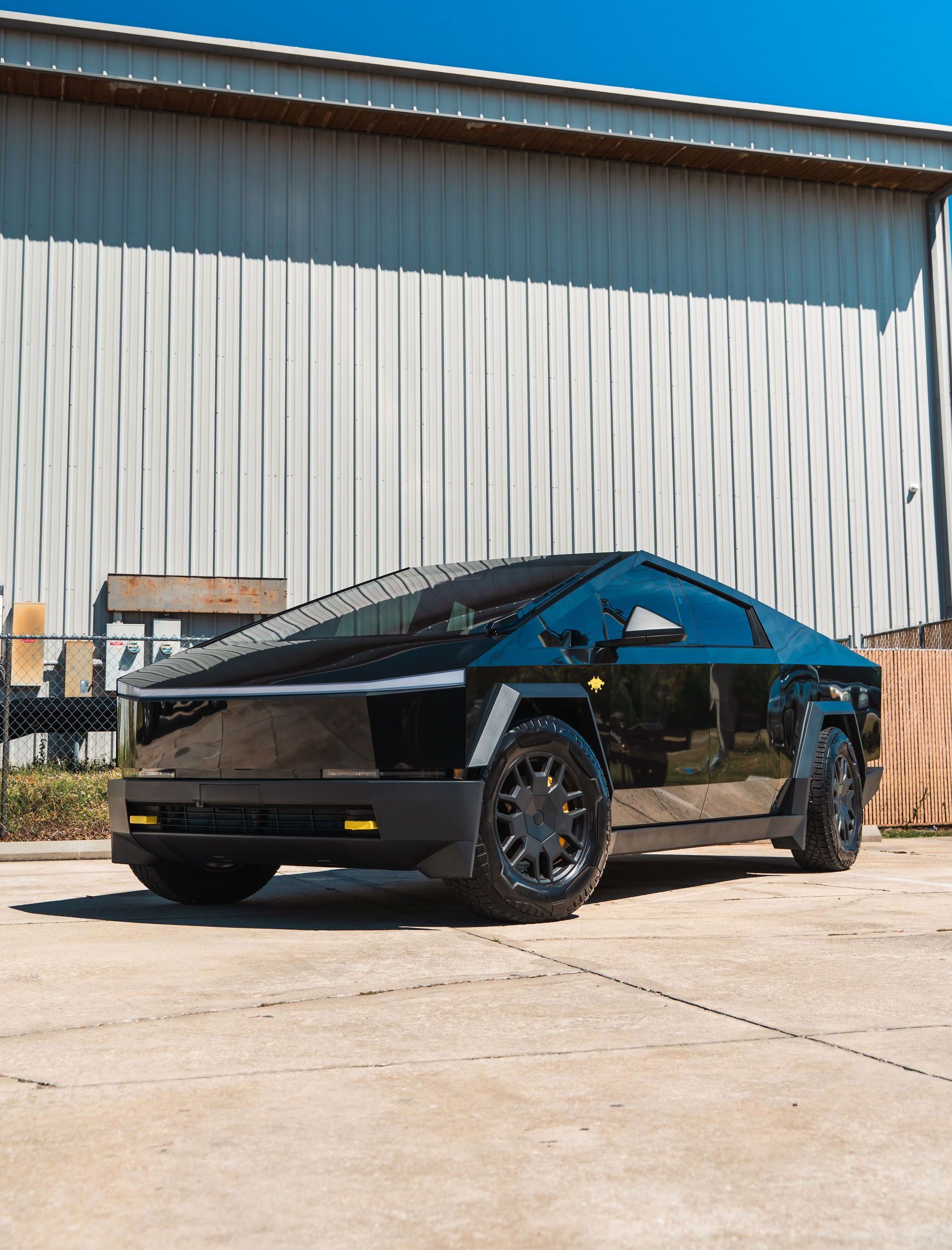 A black tesla cybertruck is parked in front of a building.