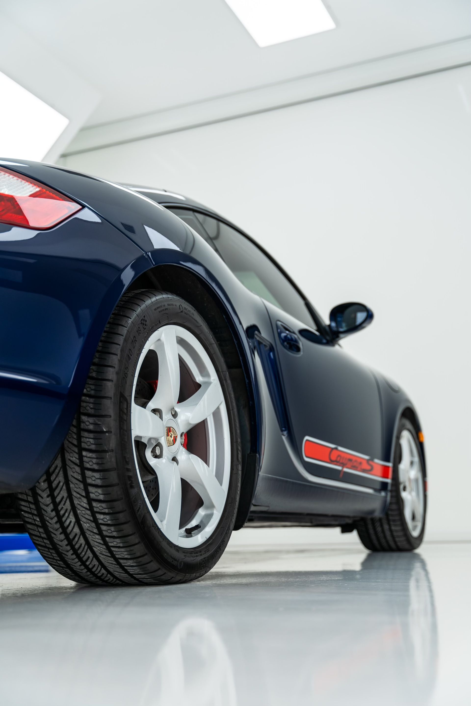 A blue porsche 911 is parked in a garage.