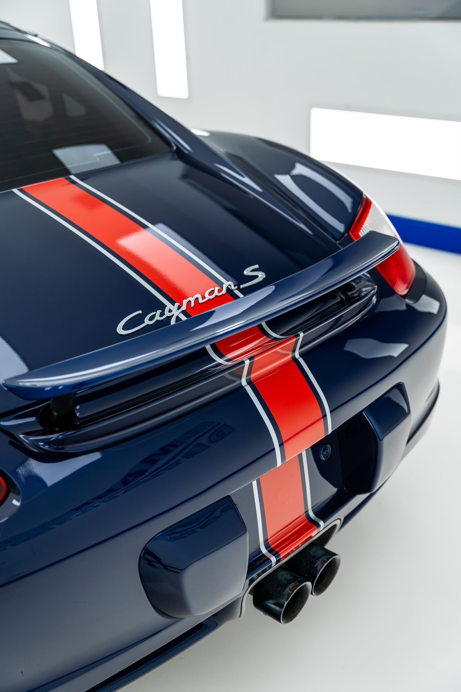 A blue porsche cayman s with red and white stripes