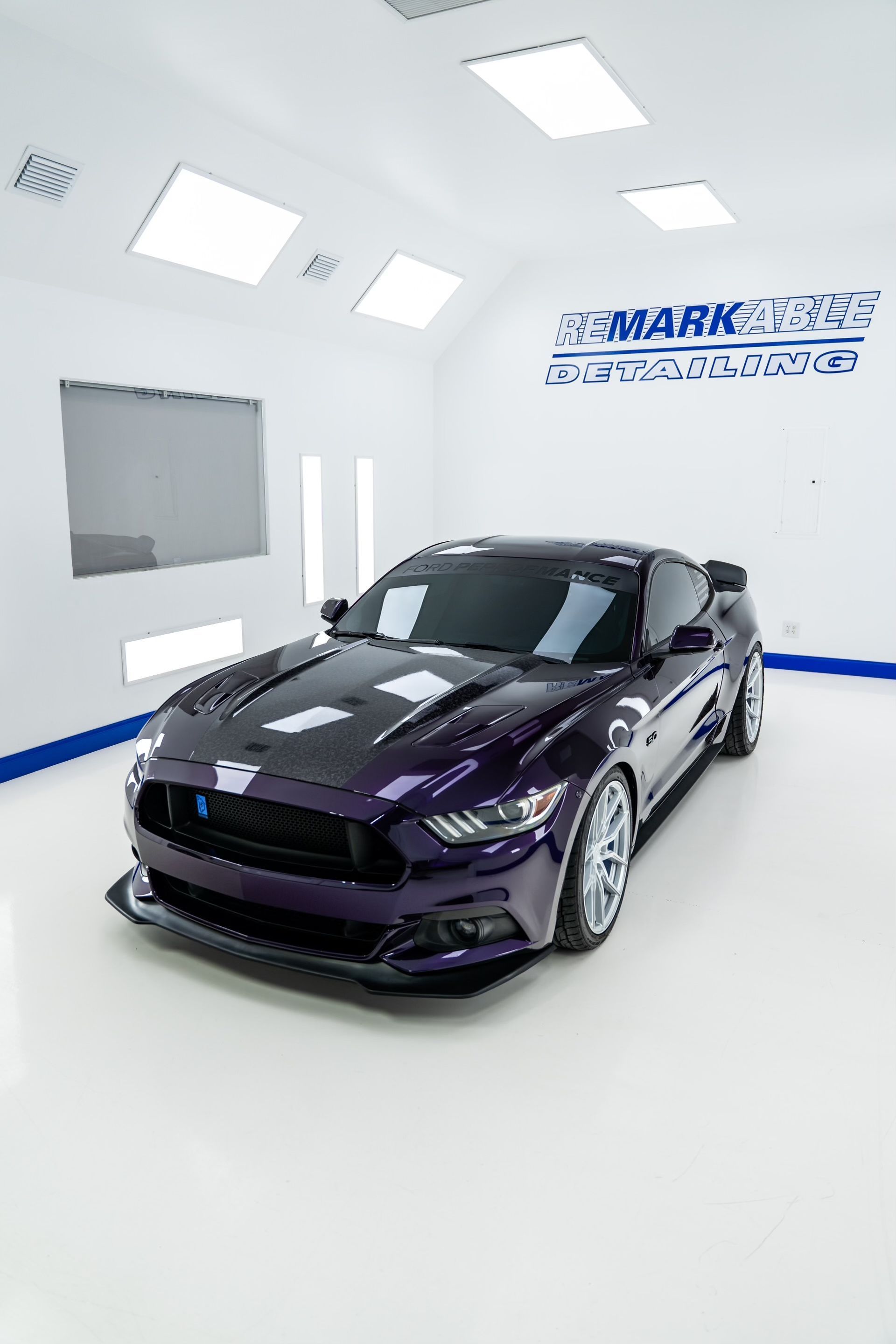 A purple mustang is parked in a paint booth.