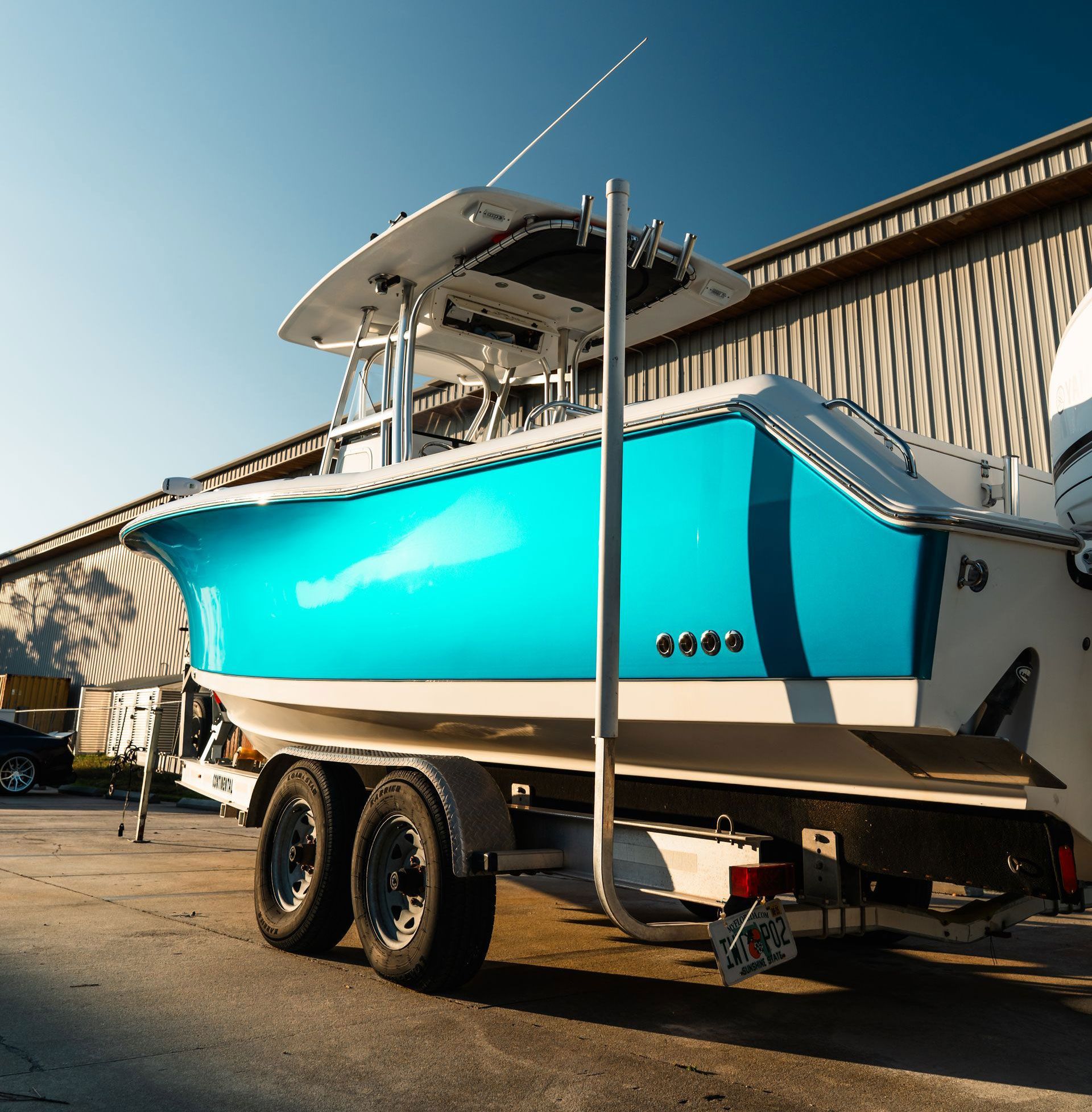 A blue boat is parked on a trailer in front of a building.