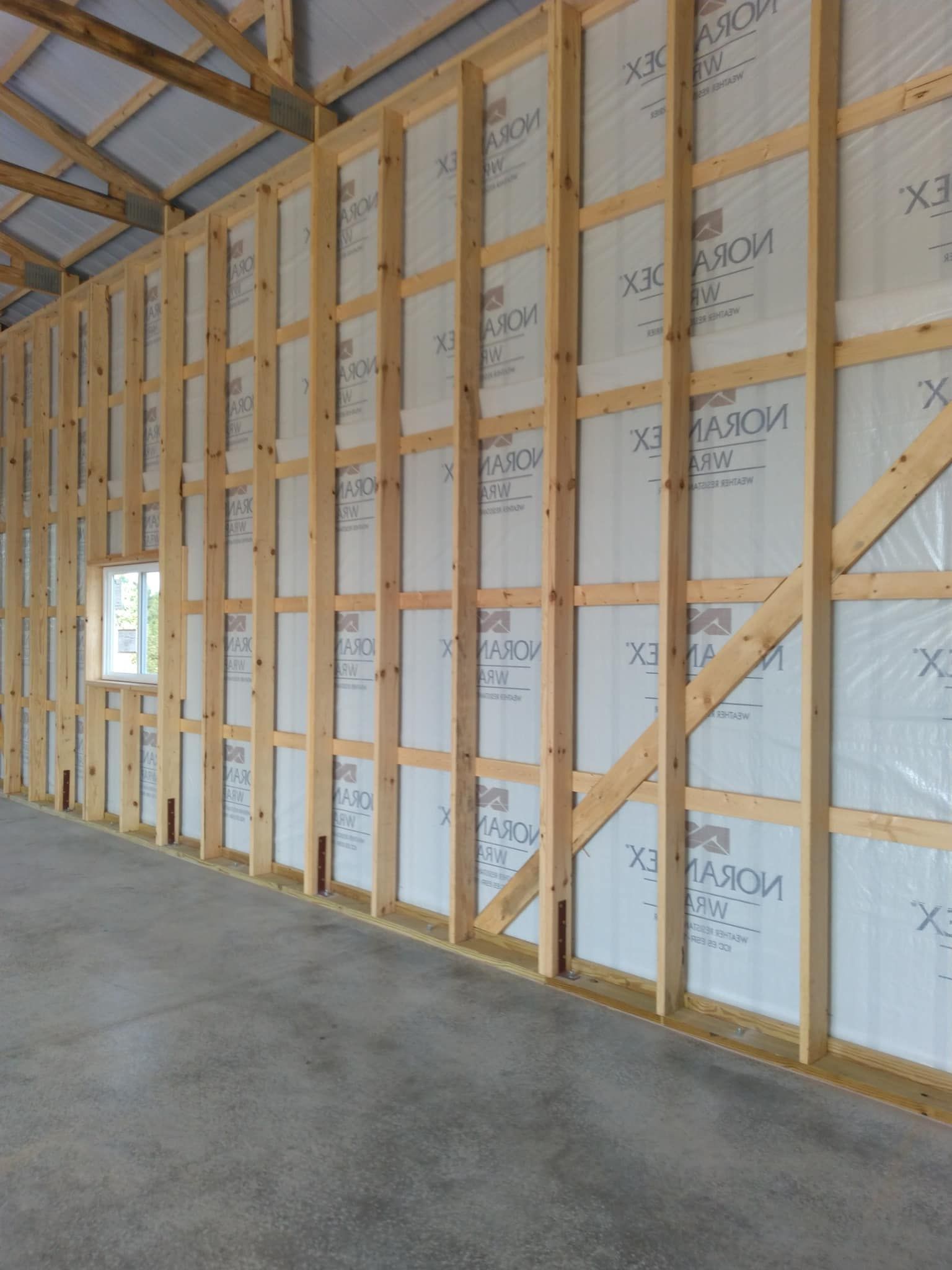 Interior view of a wooden framed building with insulation between the studs.