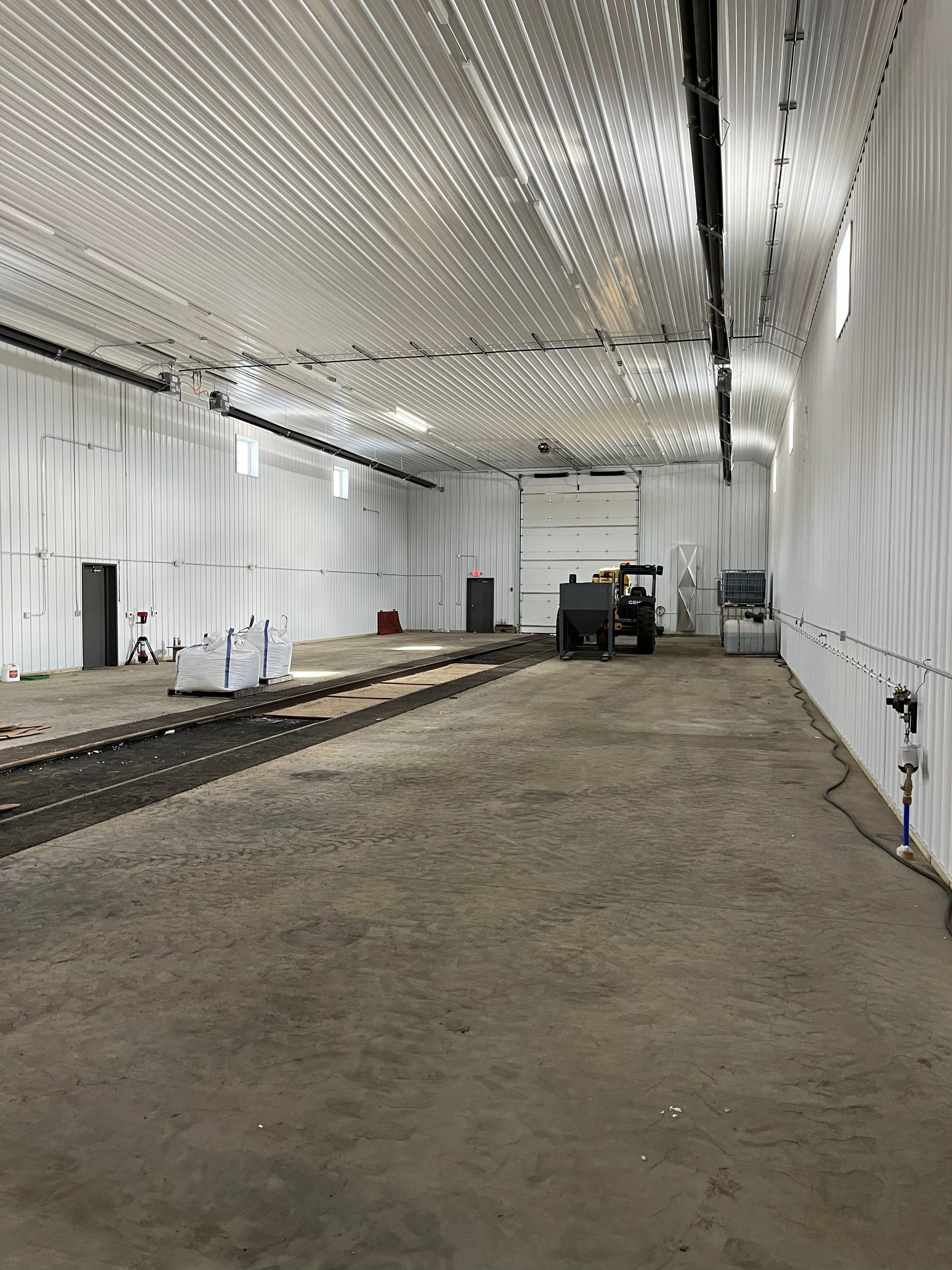 Interior of a large white warehouse with concrete floor, tractor in the center.