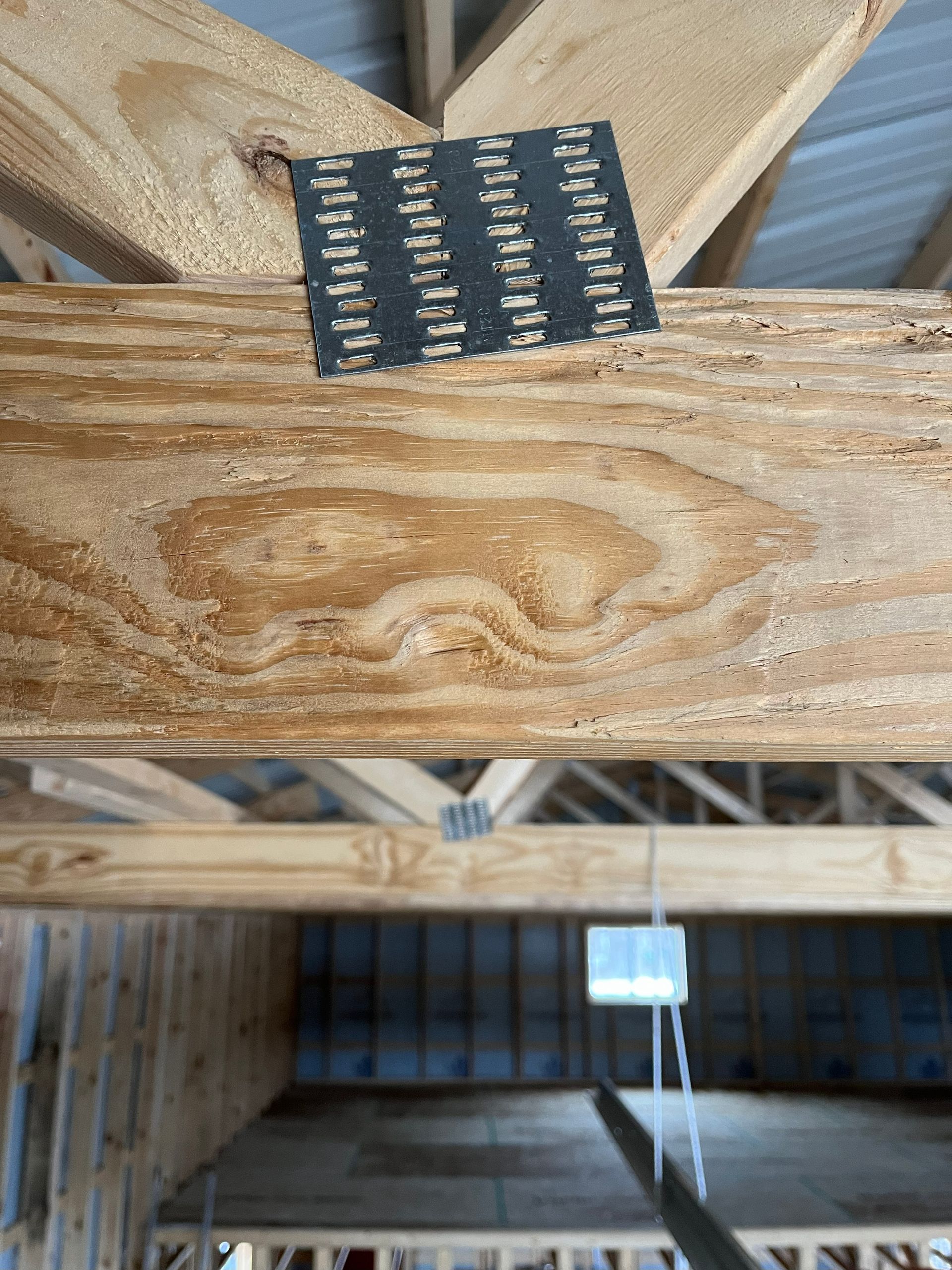 Wooden truss with metal connector plate in a building under construction.
