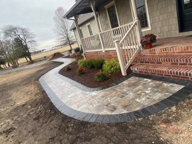 A walkway leading to a house with a porch and stairs.