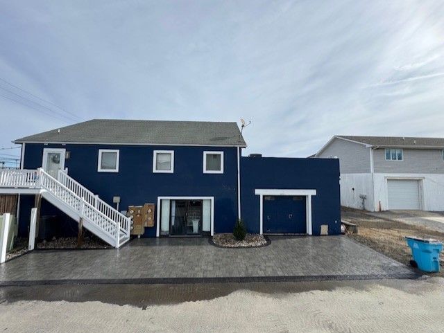 A large blue house with a white staircase and a garage.