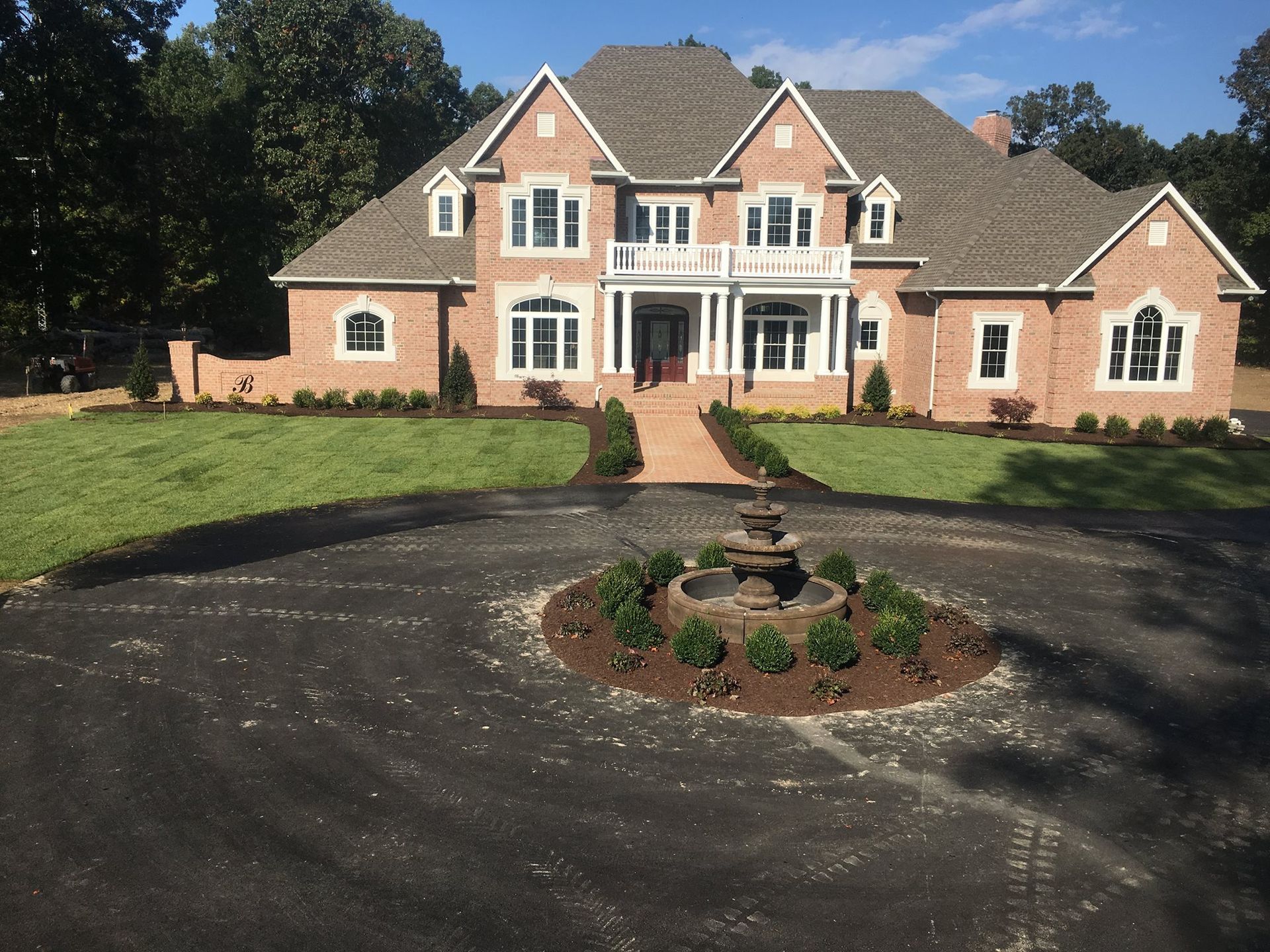 A large brick house with a fountain in front of it.