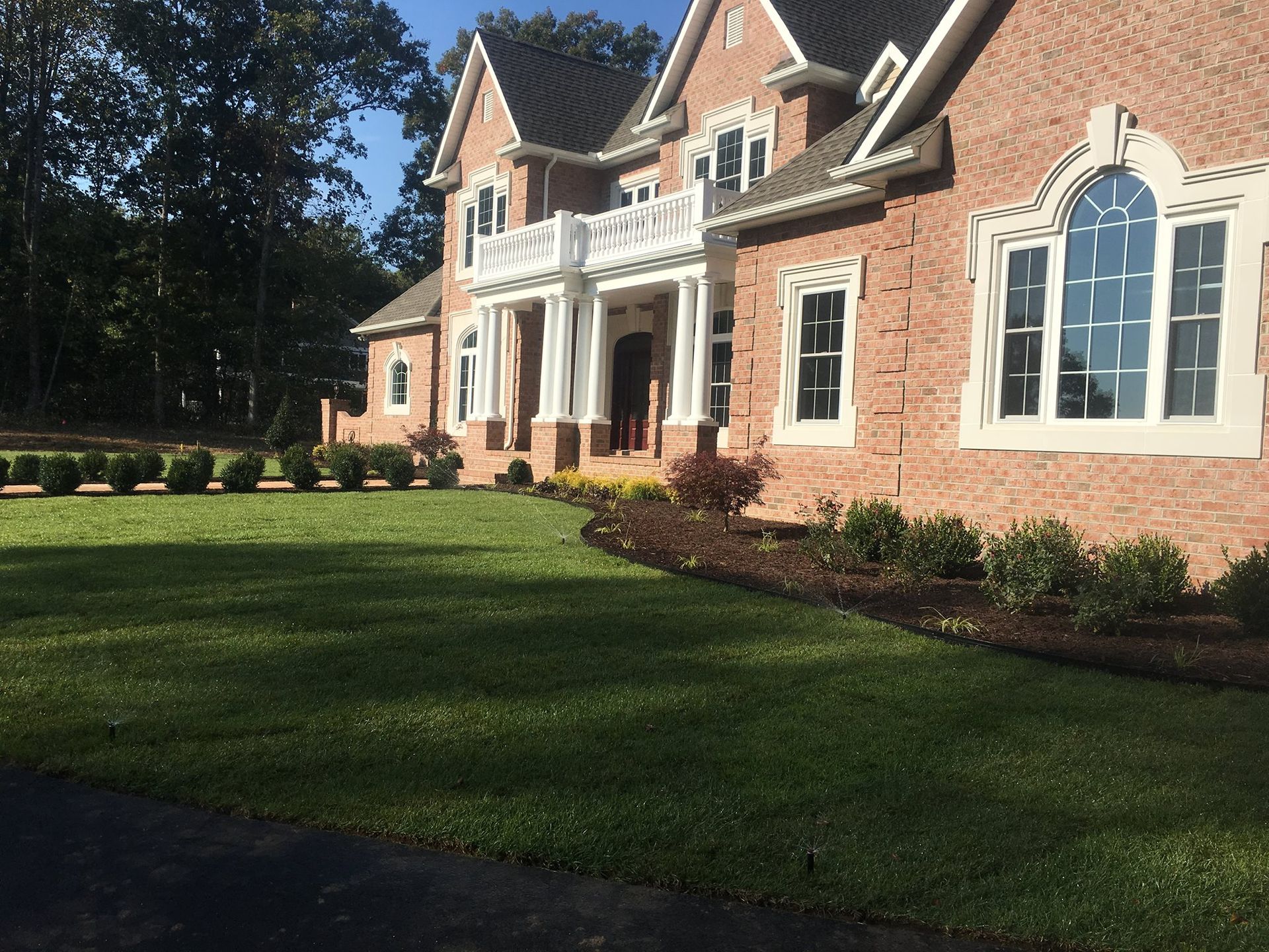 A large brick house with a lush green lawn in front of it.