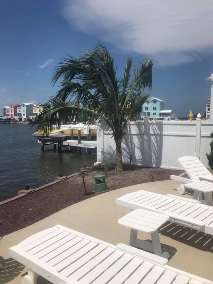 A row of white lounge chairs sitting next to a body of water.