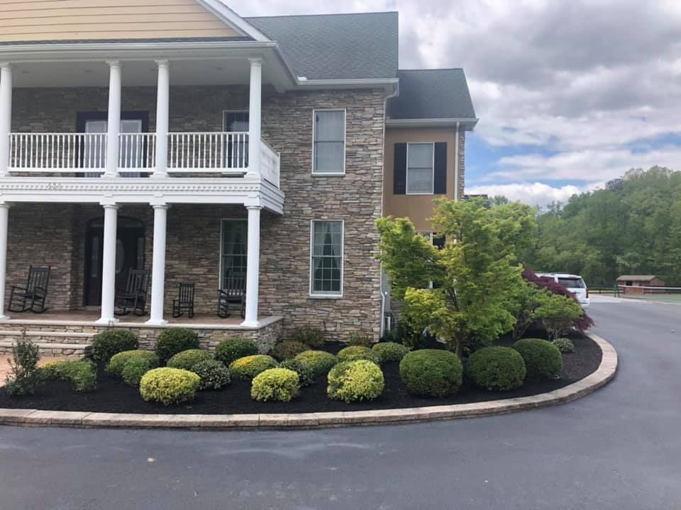 A large house with a porch and a driveway in front of it.
