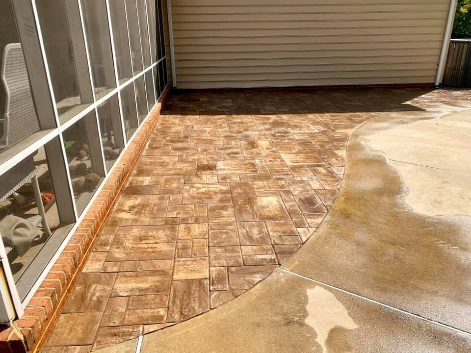 A patio with a screened in porch and a brick floor.
