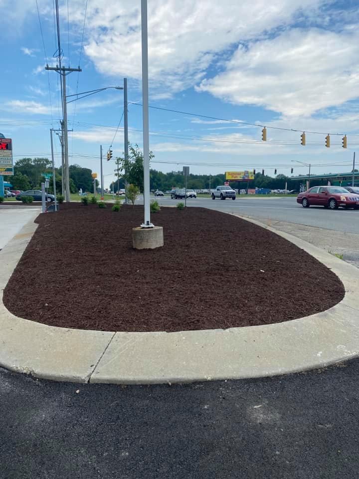 A roundabout with a lot of mulch and a flag pole in the middle of the road.