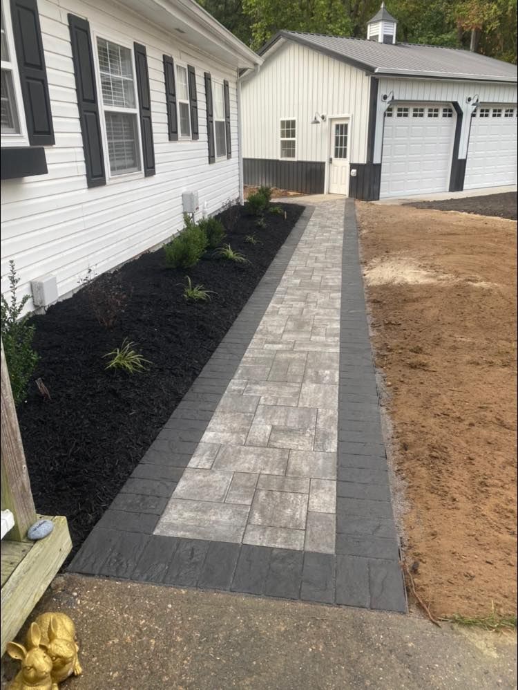 A brick walkway leading to a house with a garage.