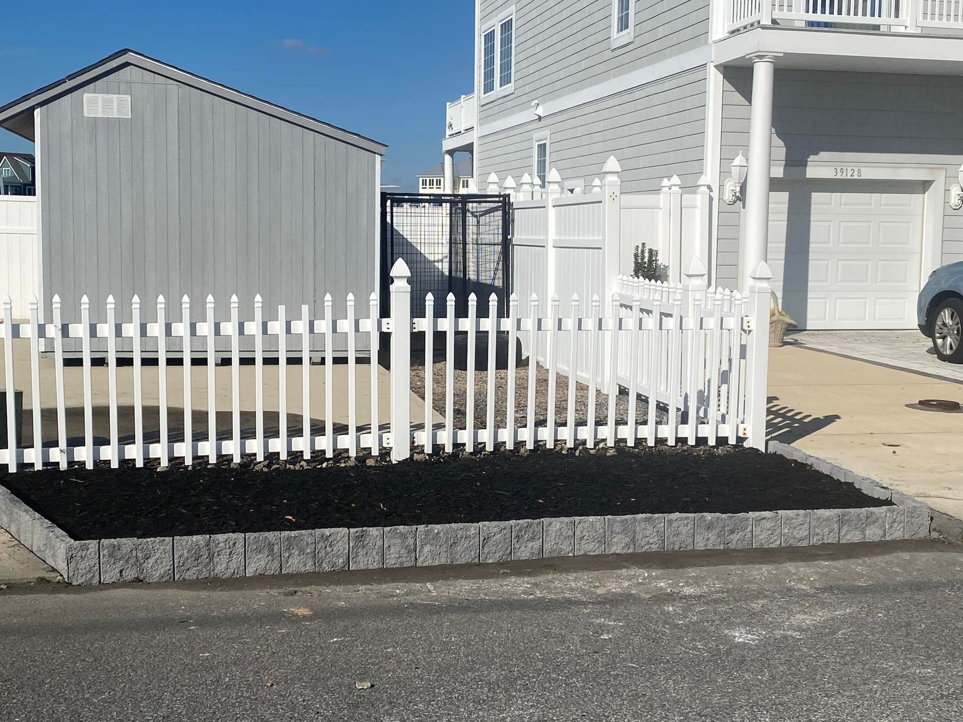 A white picket fence is in front of a house.