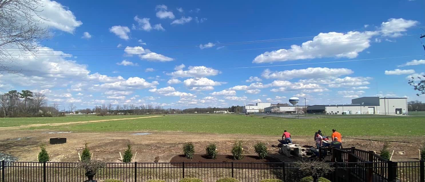 A group of people are standing in a field behind a fence.