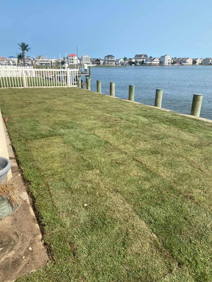 A lush green lawn next to a body of water.