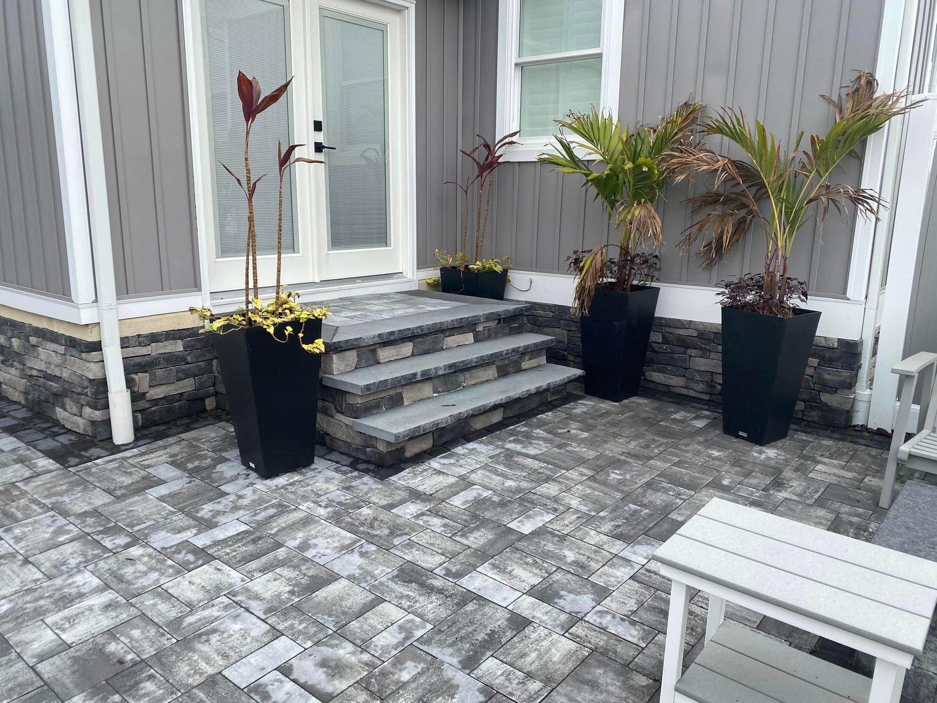 A patio with steps and potted plants in front of a house.