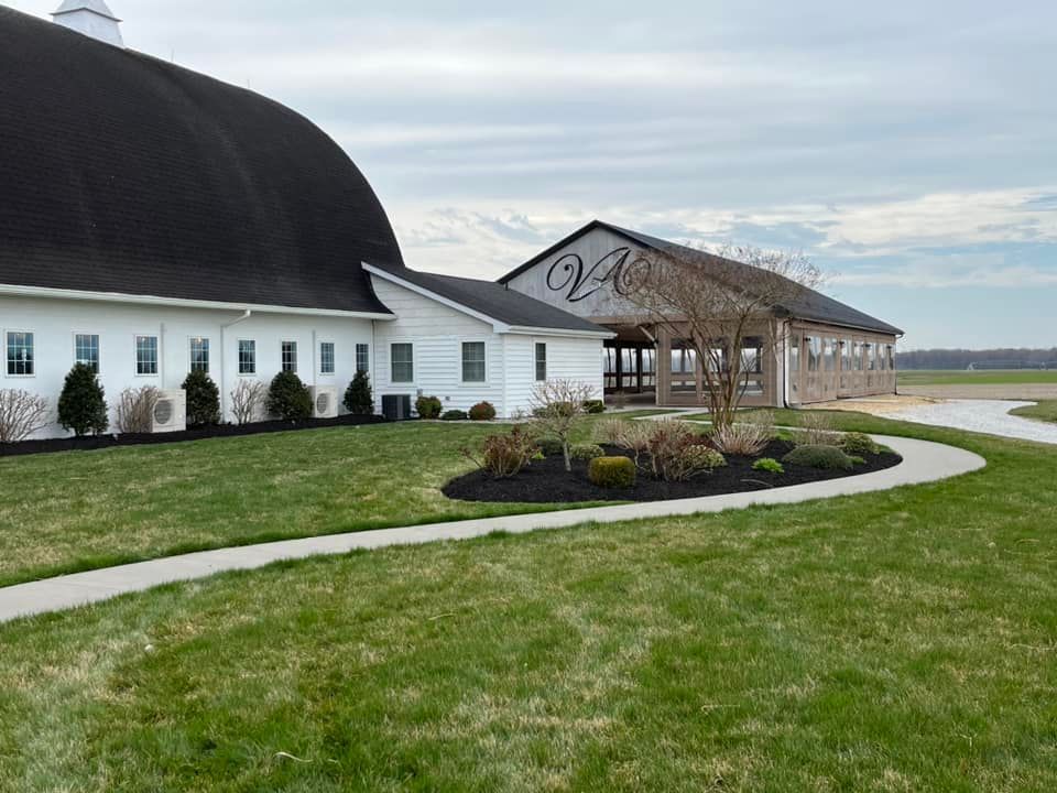 A white barn with a black roof and a walkway leading to it.