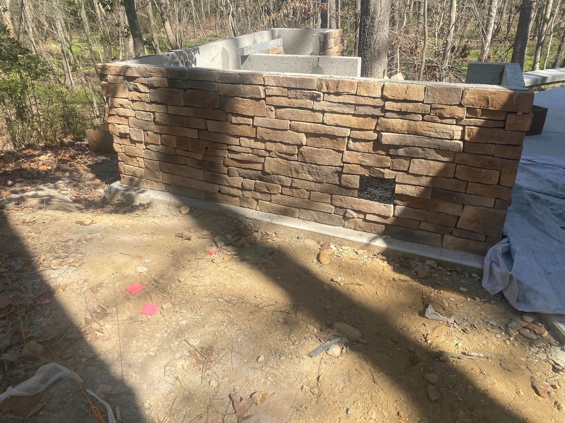 A brick wall is being built in the middle of a dirt field.
