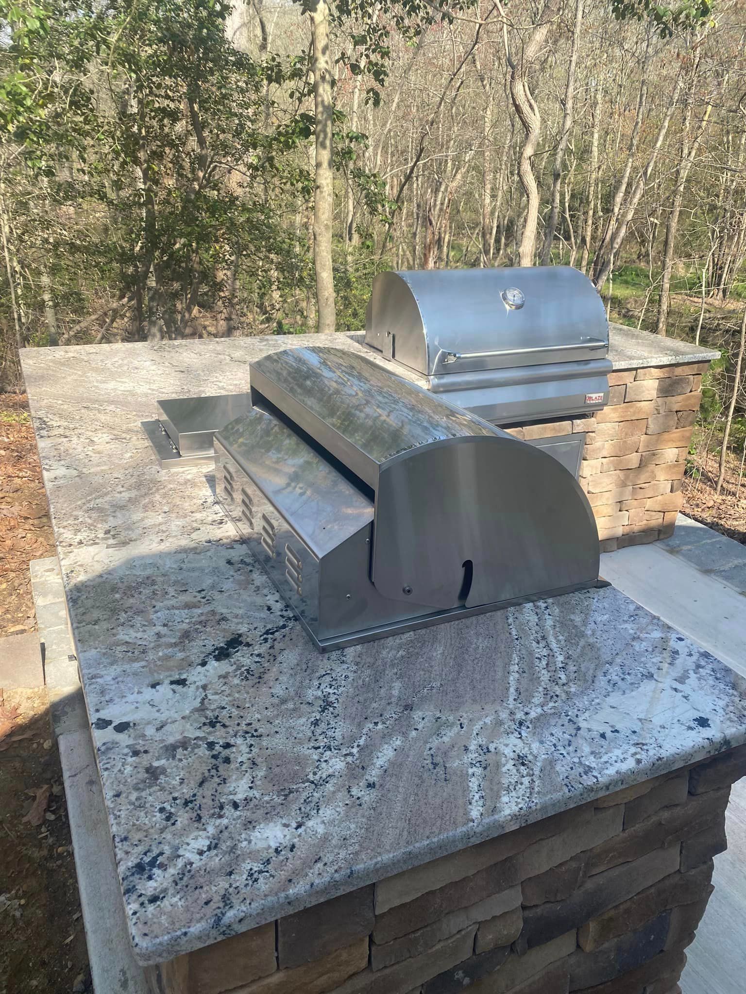A stainless steel grill is sitting on top of a granite counter top.