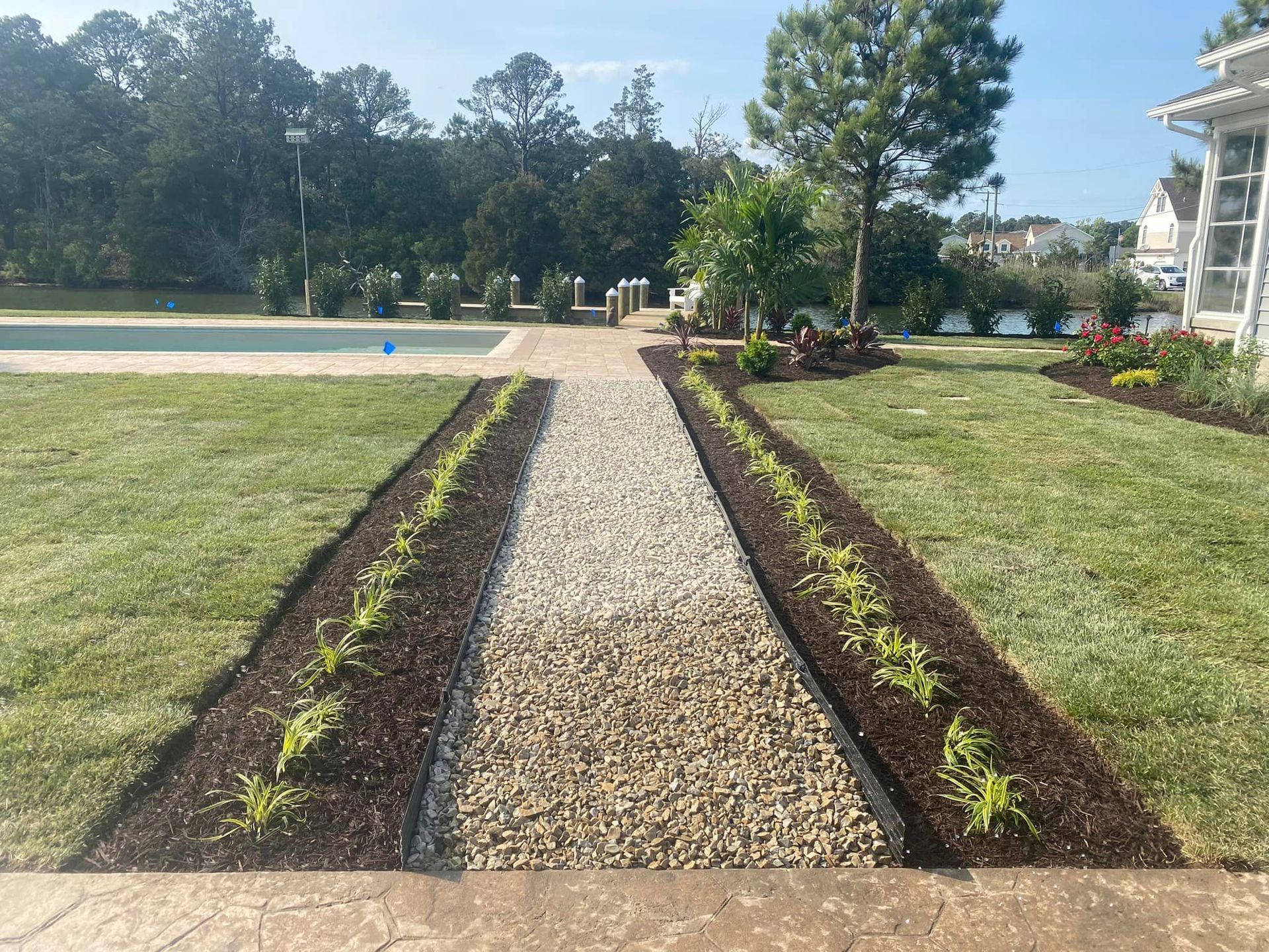 A gravel path leading to a swimming pool in a backyard.