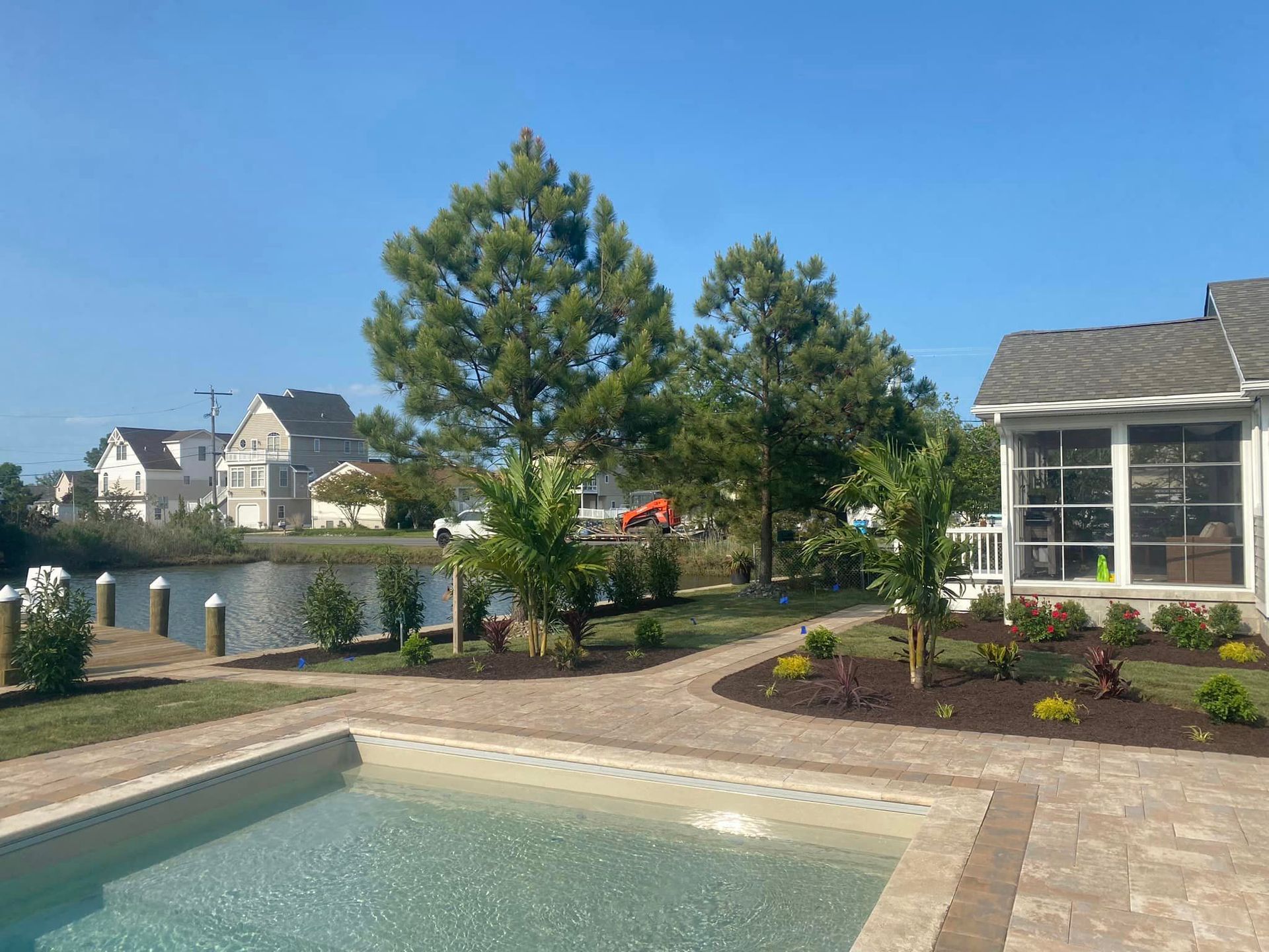 A large swimming pool is surrounded by trees and a house.