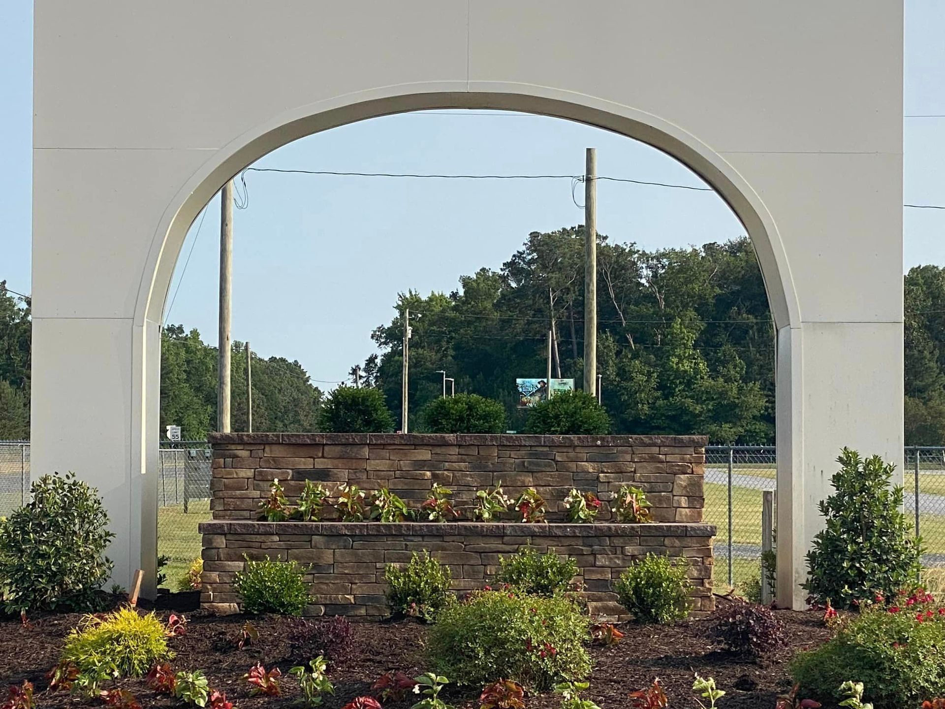 A large white archway with a stone wall in front of it.