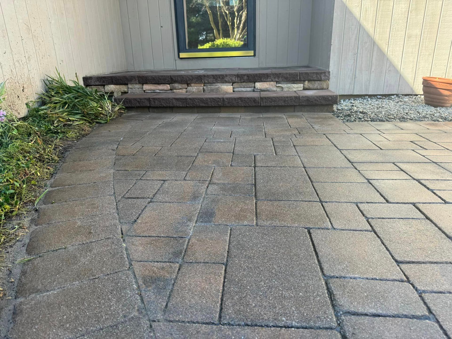 A brick walkway leading to a house with a picture on the wall.
