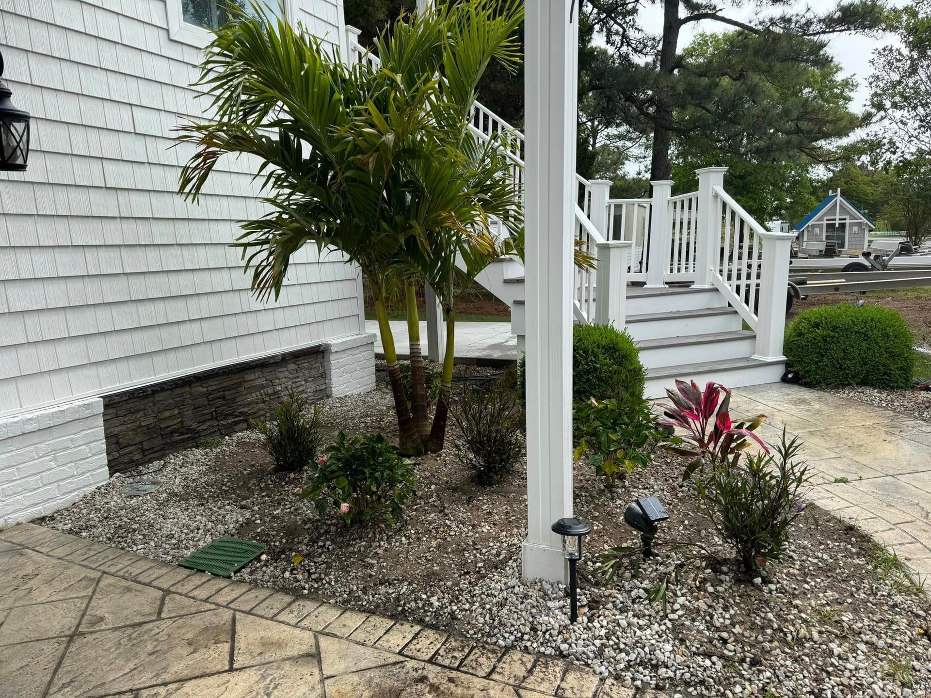 A white house with stairs and a garden in front of it.