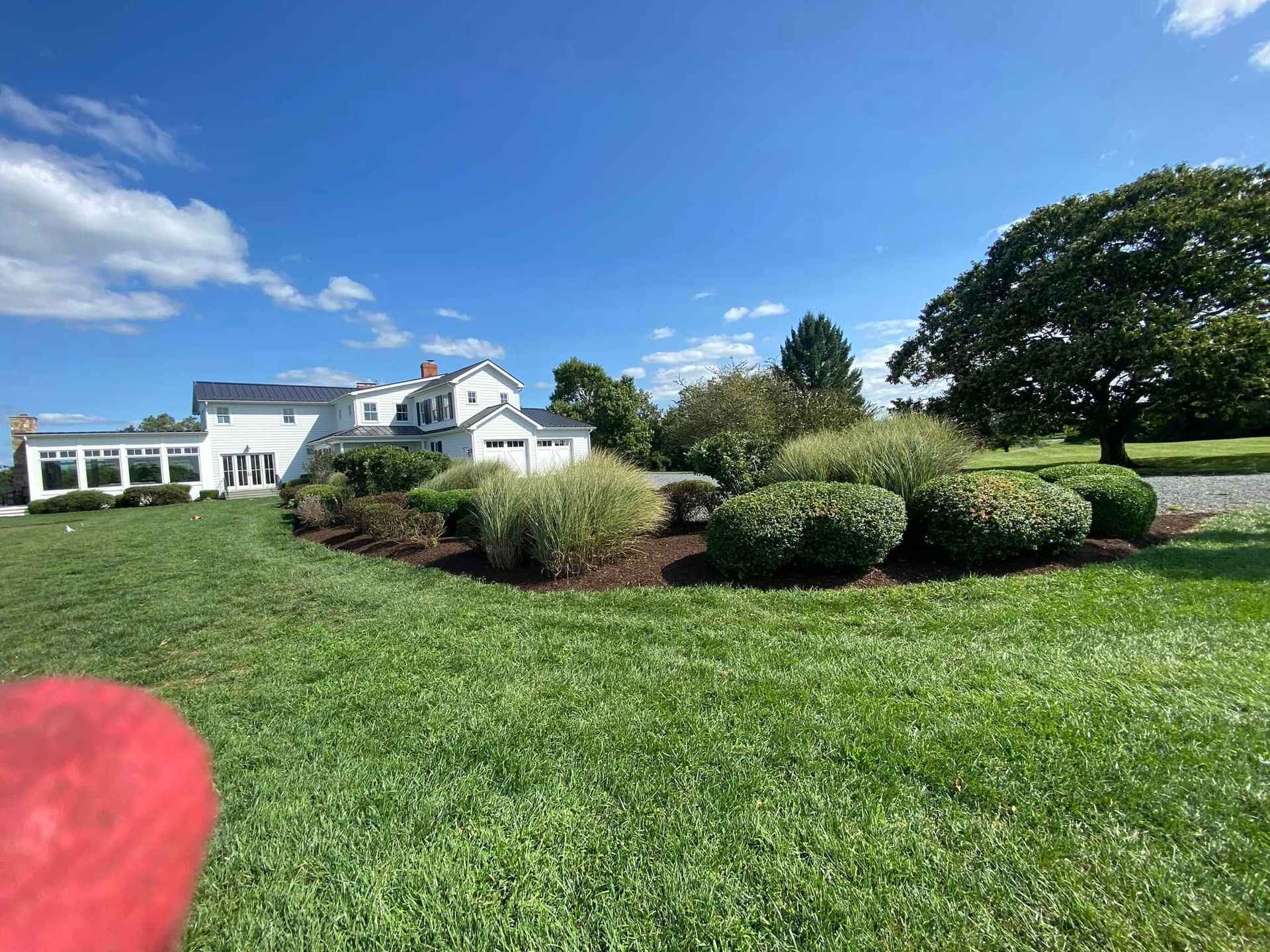 A person is throwing a frisbee in front of a large white house.