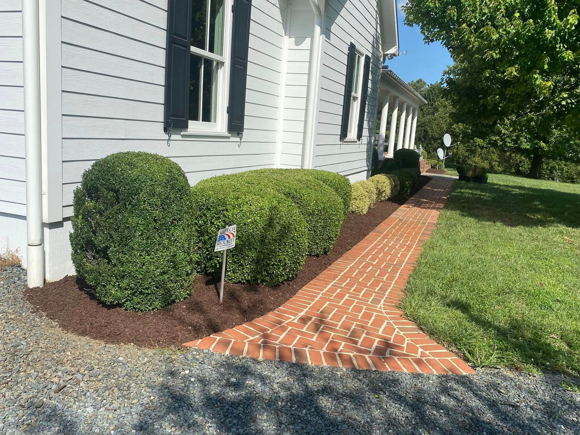 There is a brick walkway leading to the front of the house.