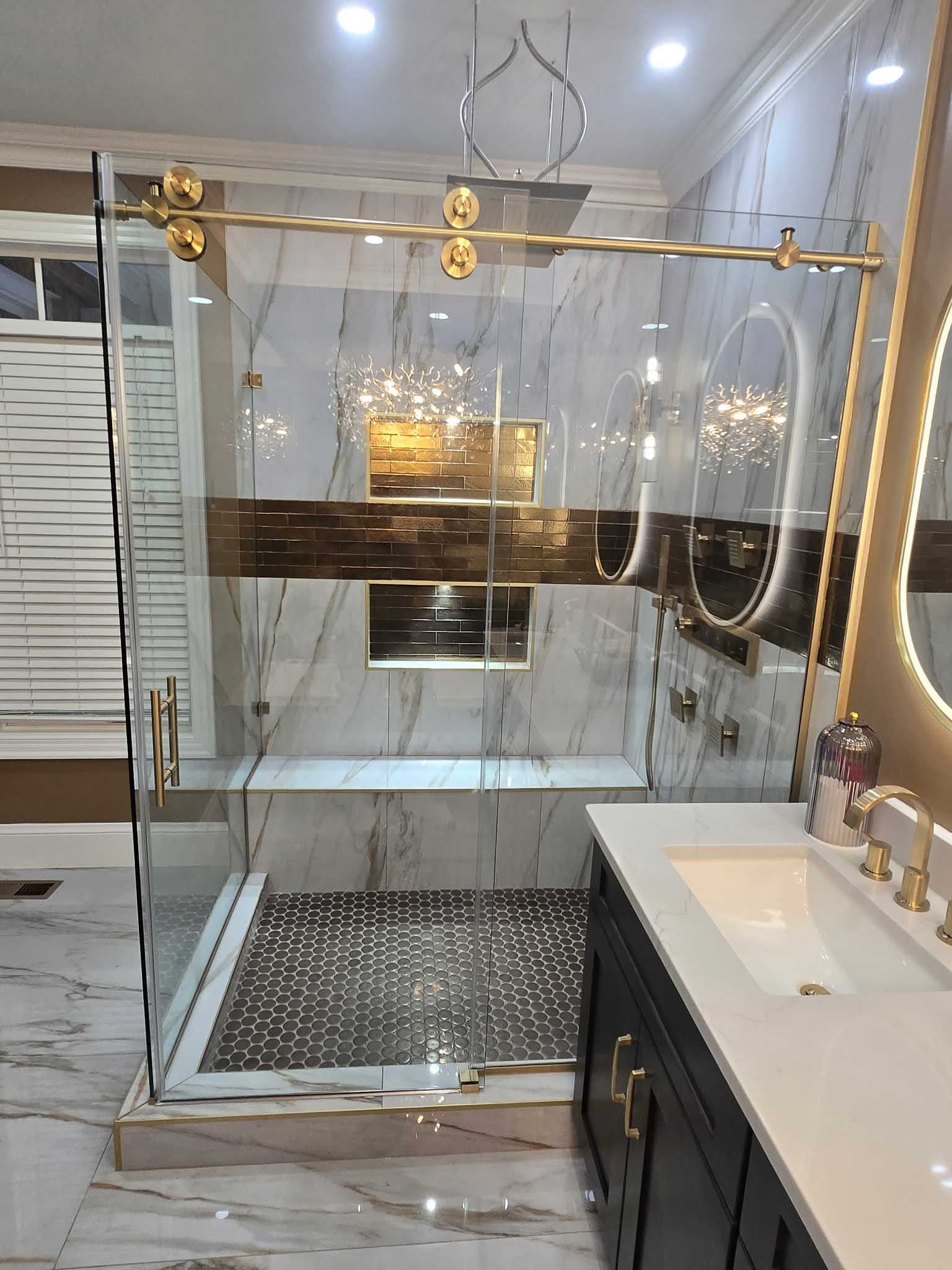 Modern bathroom with a marble-tiled walk-in shower featuring gold hardware and a dark wood vanity with white countertop.