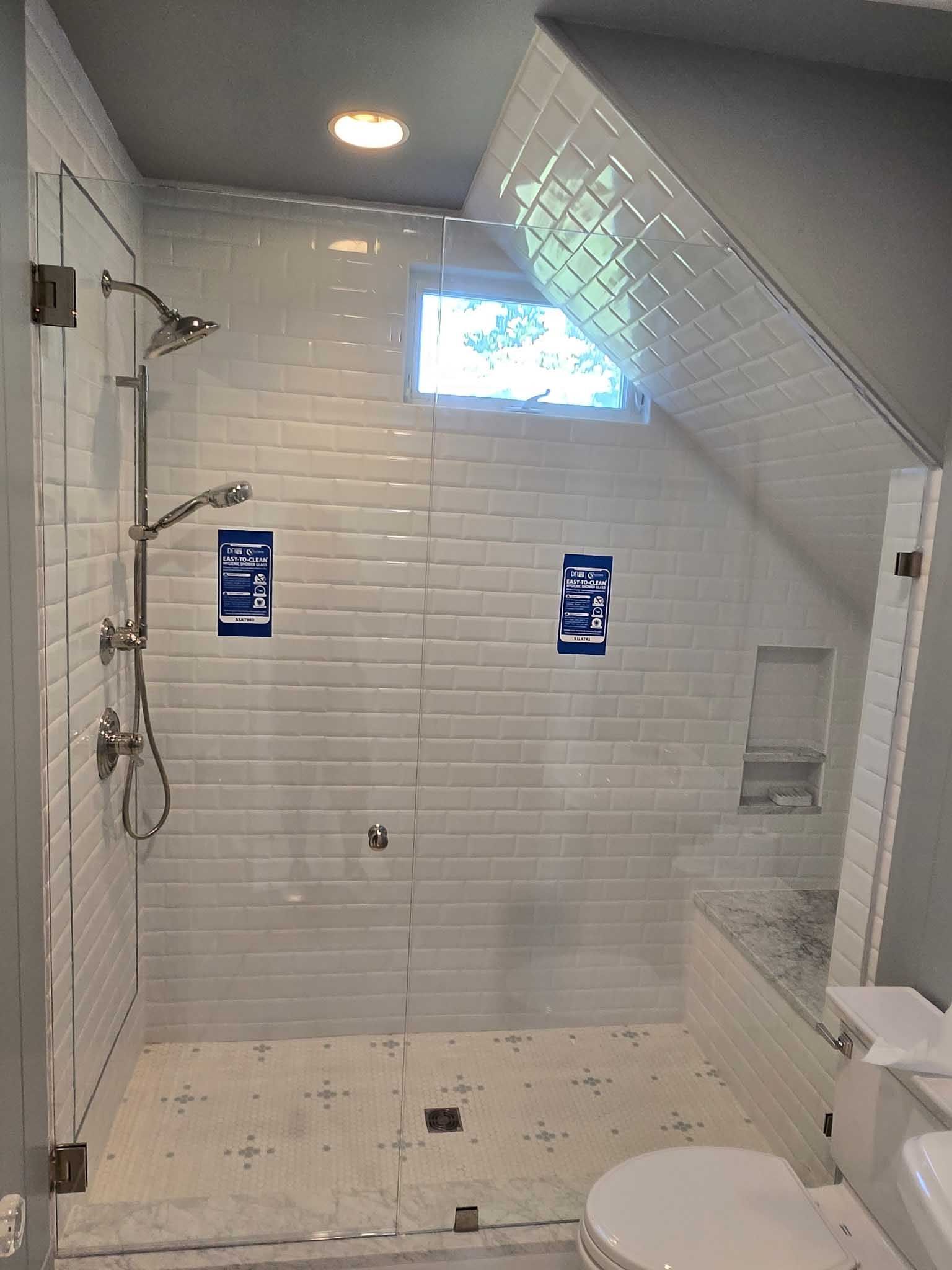A shower with white subway tile walls, a handheld showerhead, a small square window, and a built-in tiled bench seat.