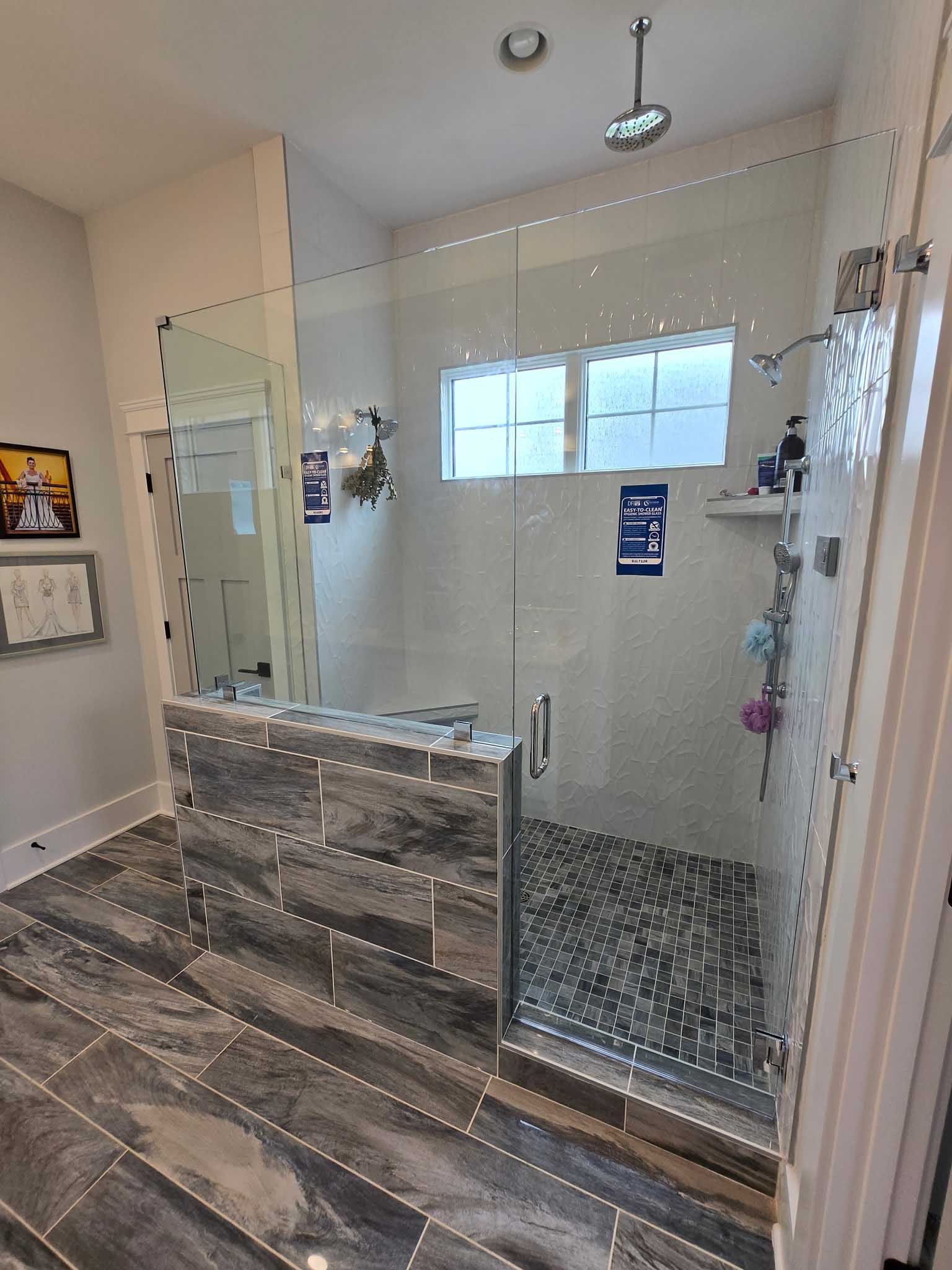 A tiled walk-in shower with glass walls, featuring dark grey flooring and a rainfall showerhead in a modern bathroom.