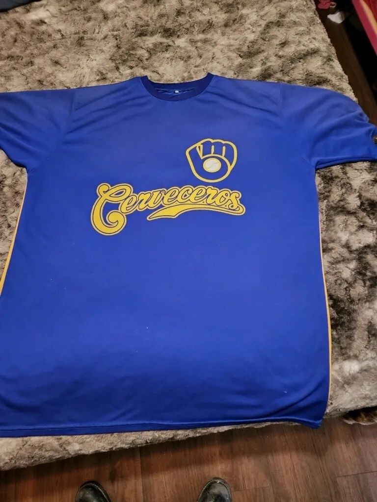 Blue T-shirt with a yellow Milwaukee Brewers logo laid flat on a carpet.
