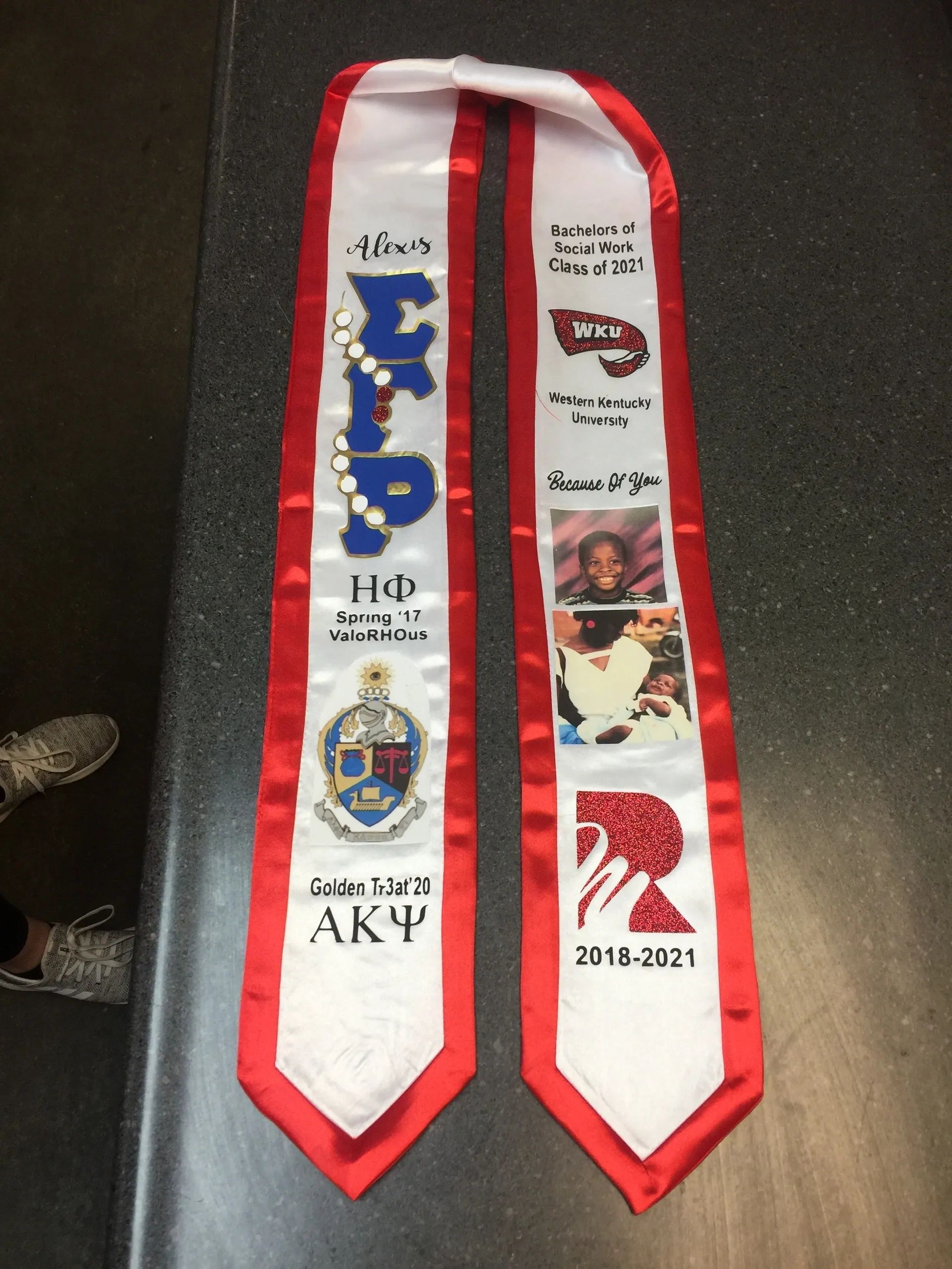 Two red-and-white Greek life stoles with Greek letters and badge patches laid on a dark surface