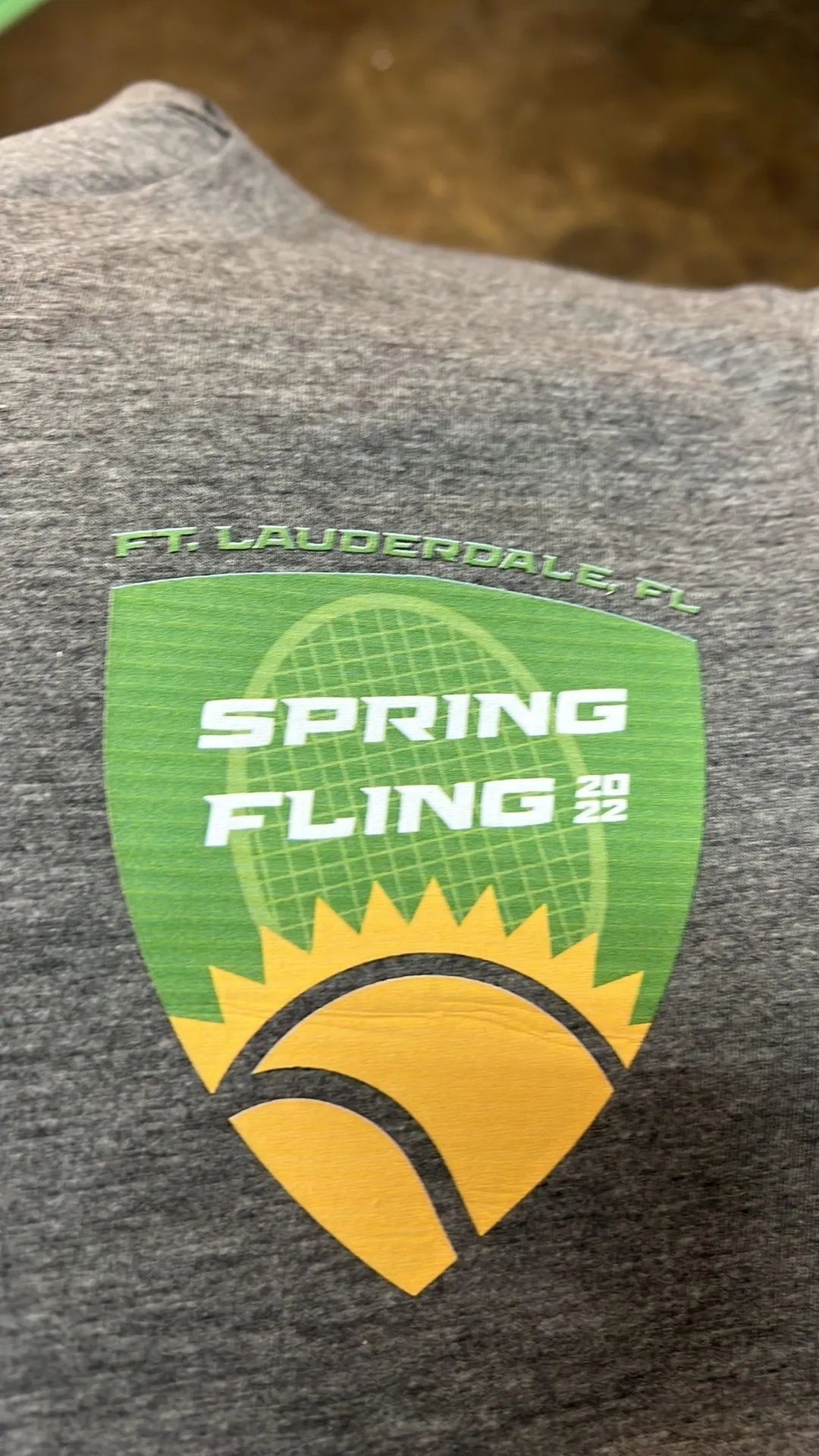 Gray shirt with a green and yellow Spring Fling logo and sunburst design