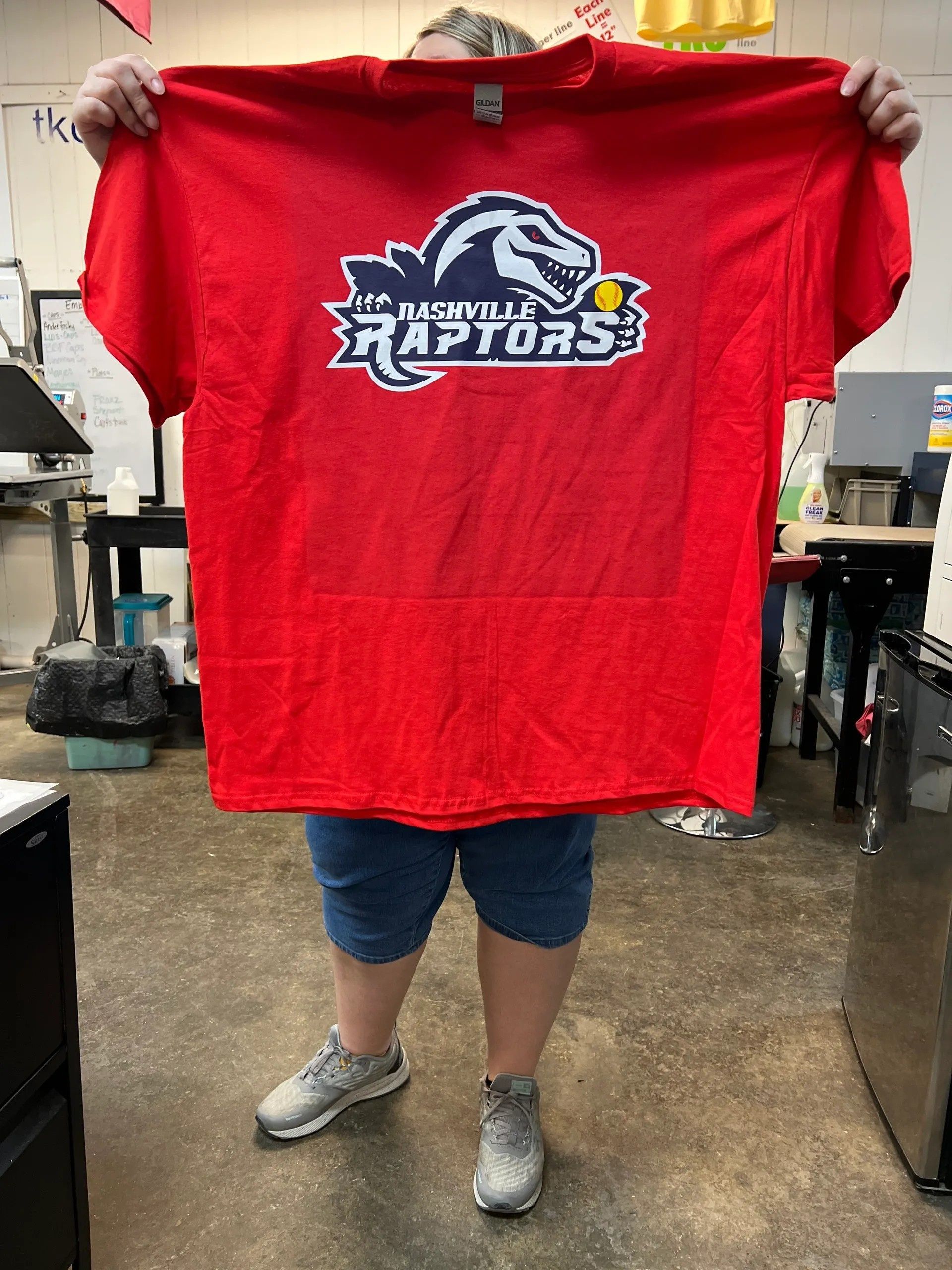 Person holding up a red Toronto Raptors T-shirt indoors