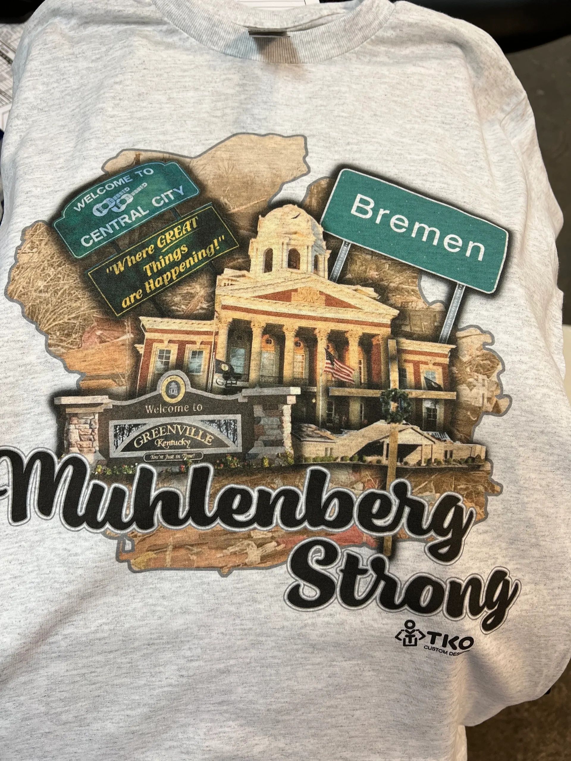 Mühlenberg Strong T-shirt graphic with a historic building and “Bremen” sign in tan, green, and black